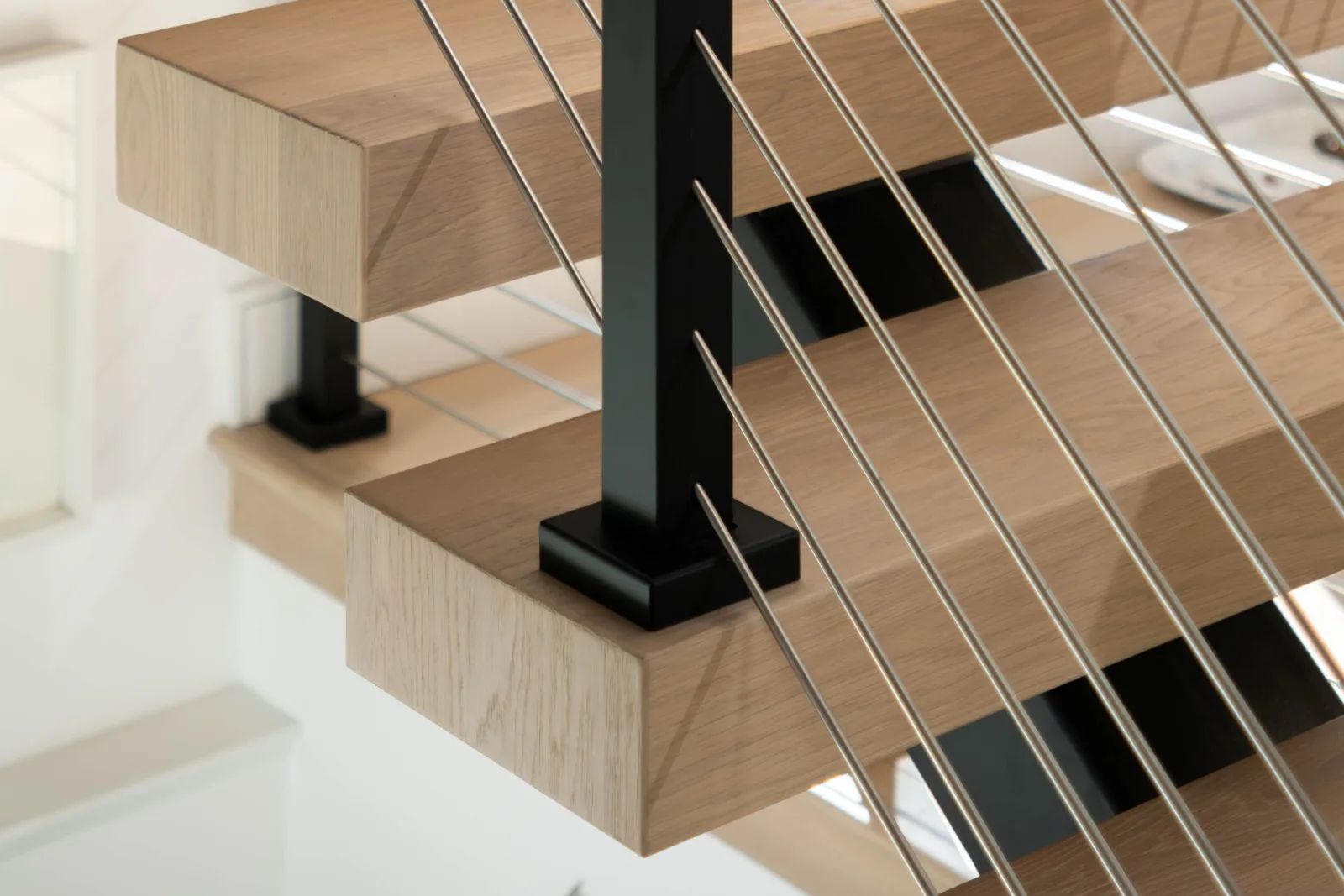 Tread end detail where a black post base plate sits beside stainless rods