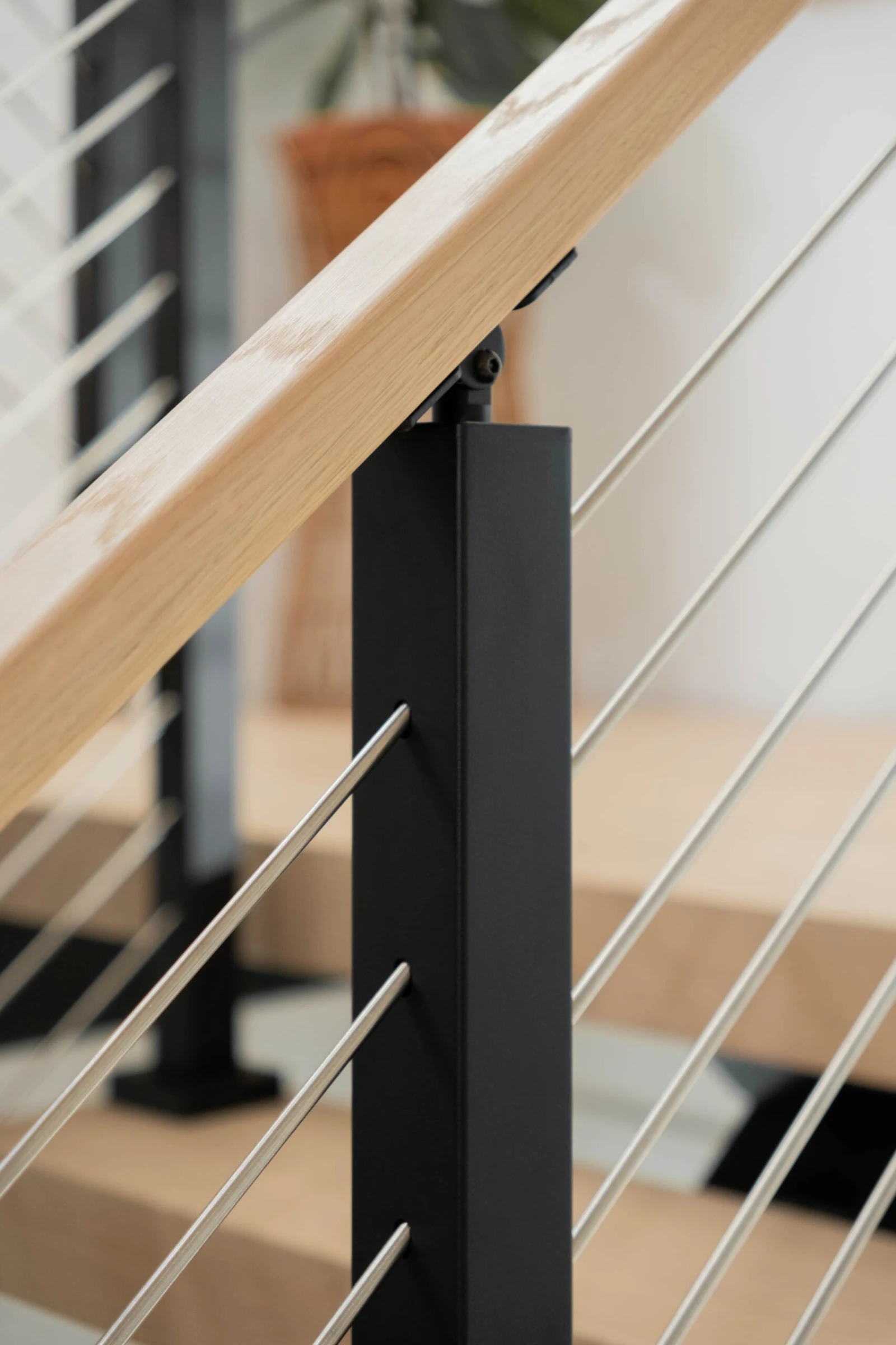 Close view of a black post joining the wood top rail above angled rods