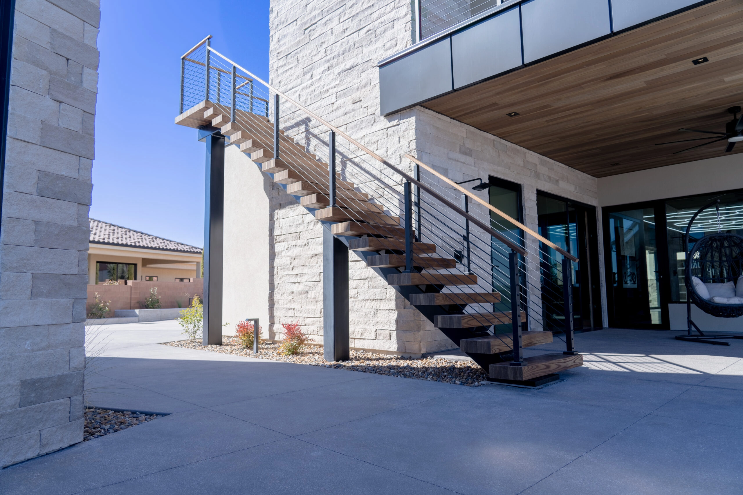 Full run of the outside stair below a cable-railed upper balcony
