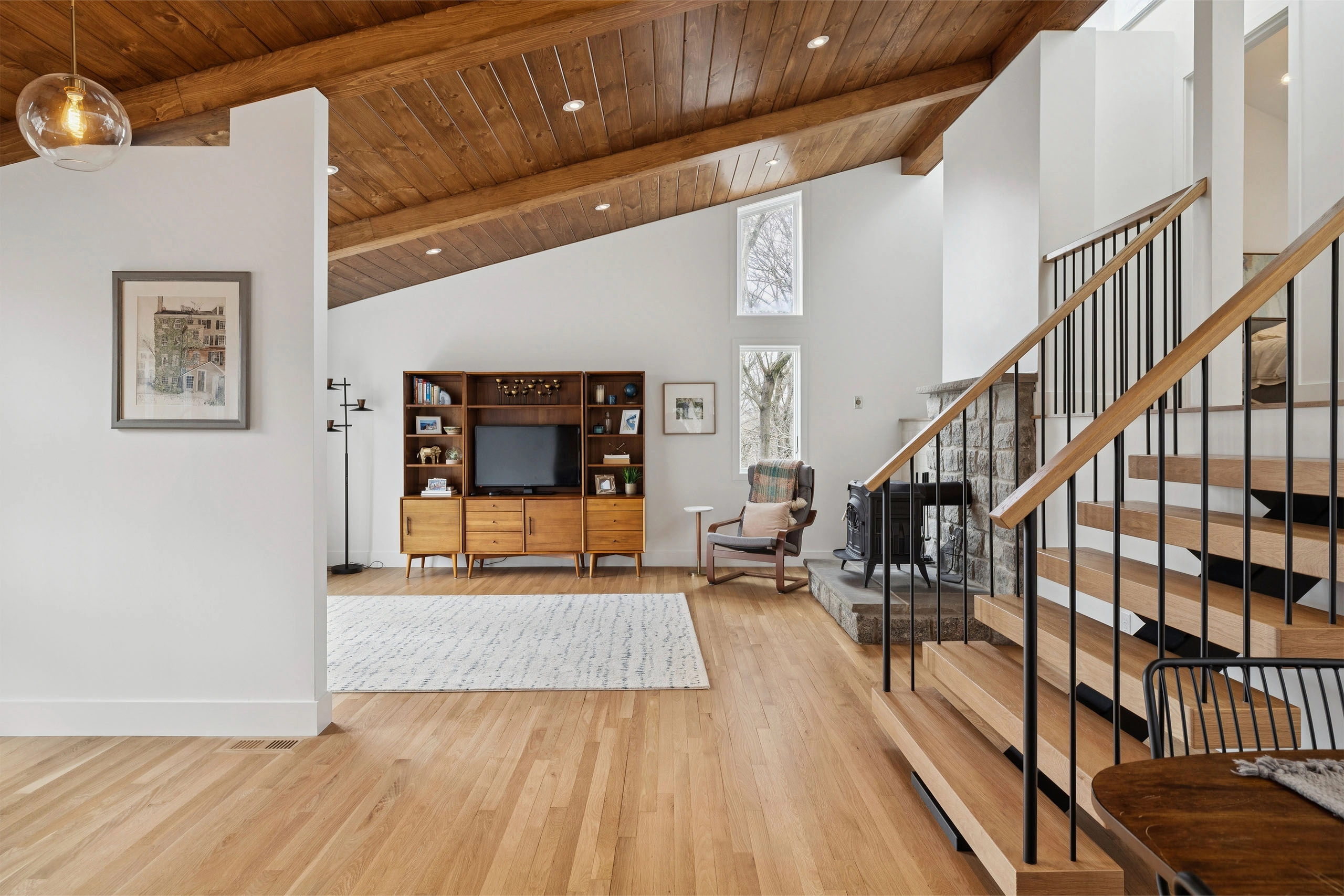 Living room view with thin black balusters and a wood handrail on the open stair