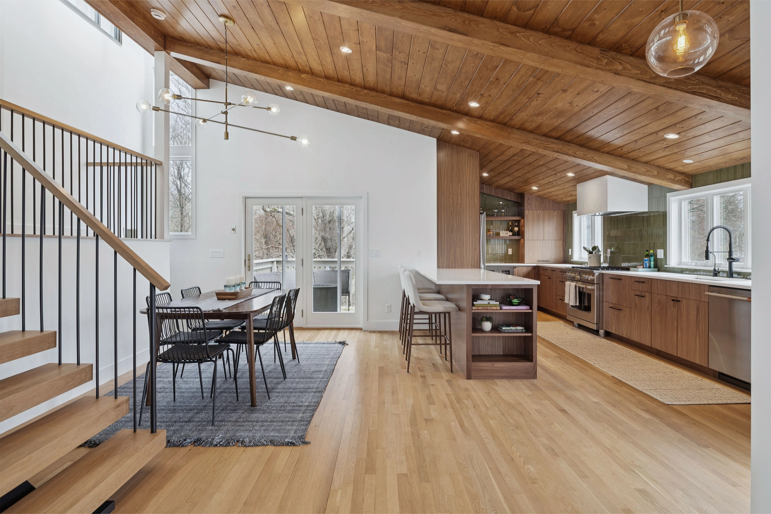 Stair balustrade in the foreground with the kitchen island and dining table beyond