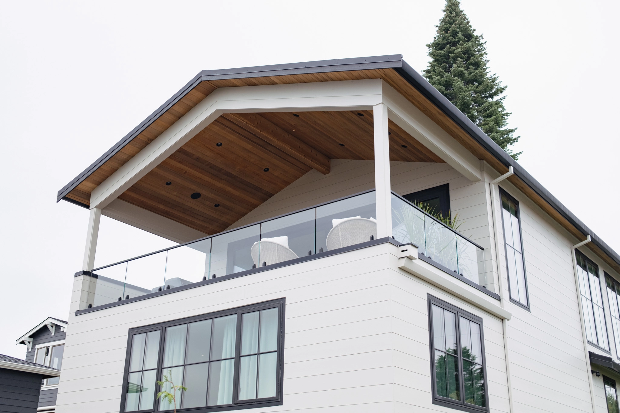 Upper deck glass railing tucked under a gabled roof with warm wood soffit