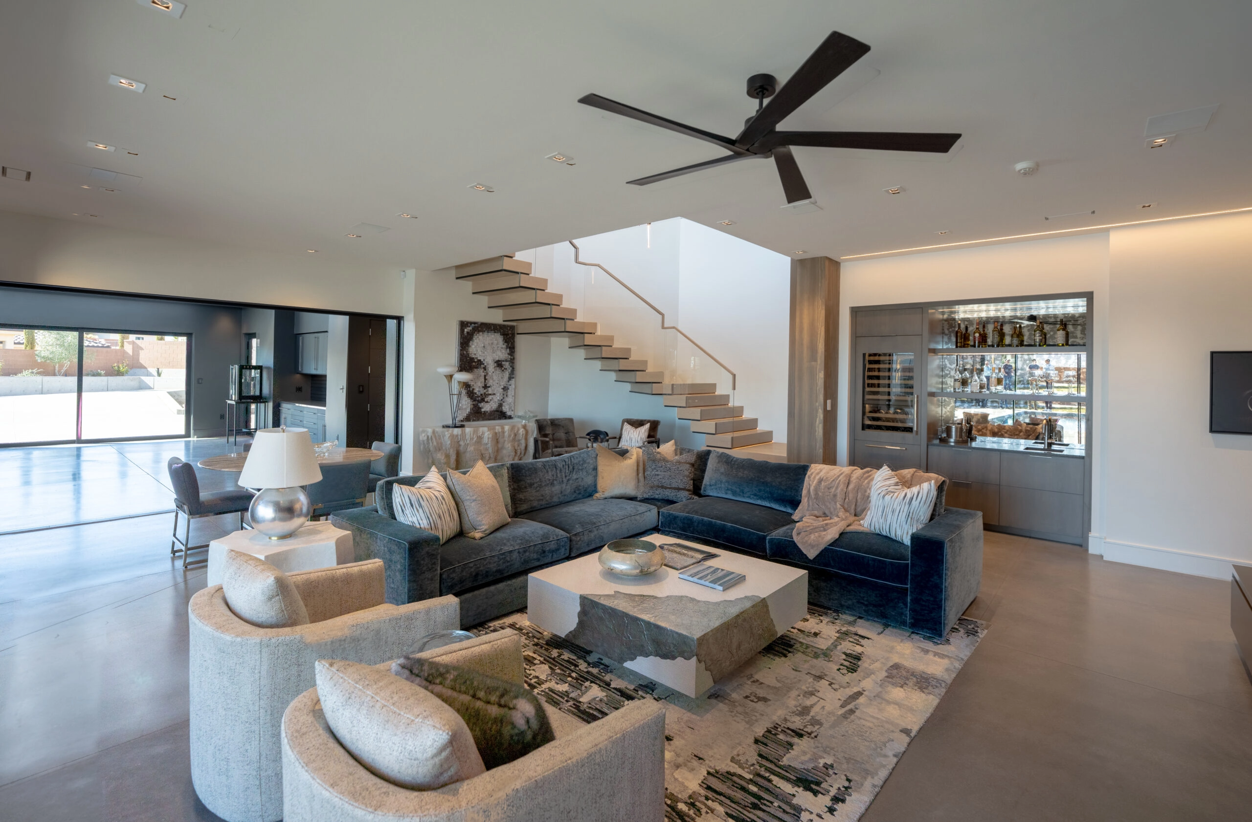 Great room with sectional seating and the pale floating stair rising behind it