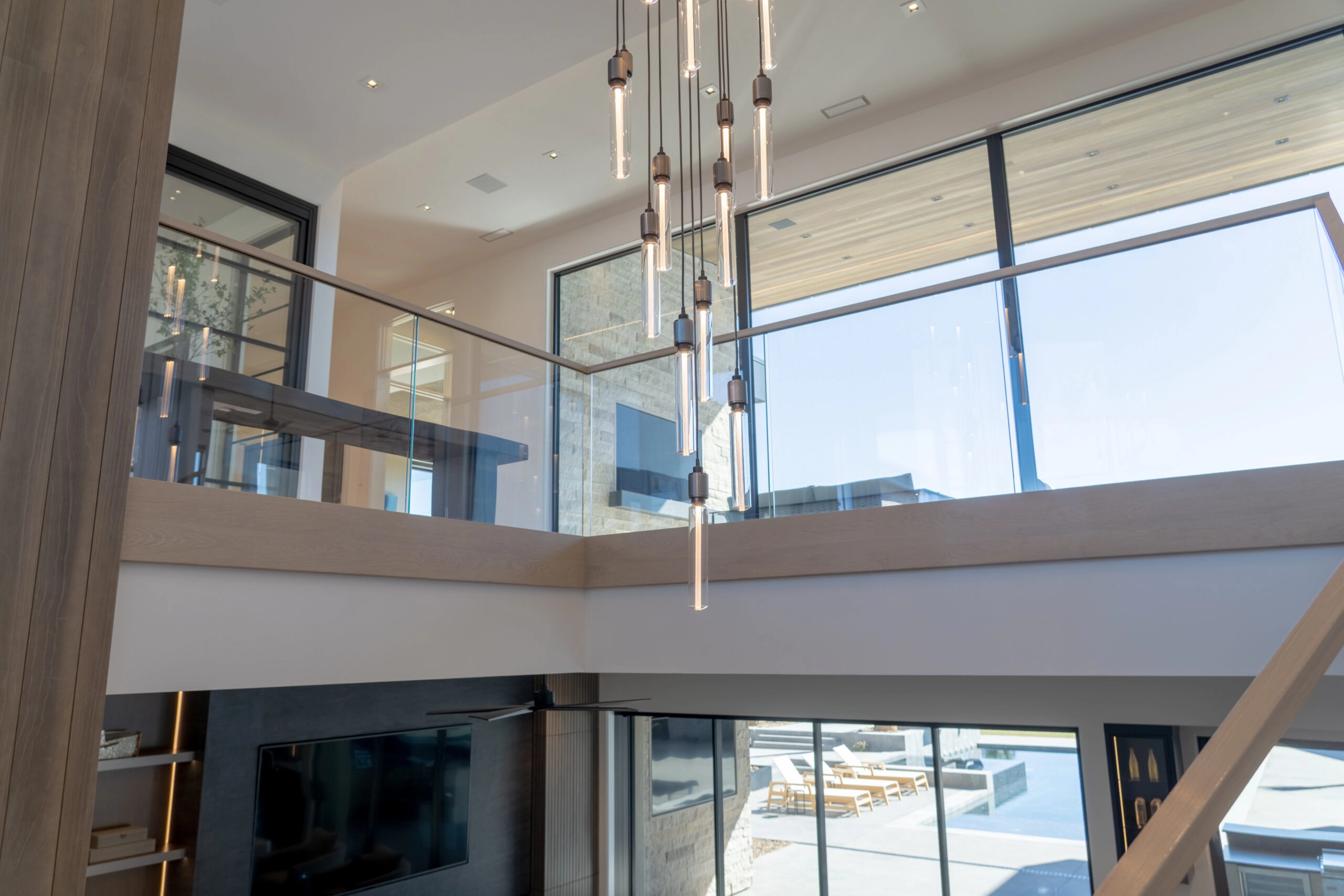 Upper level glass railing seen across a double height space toward the windows