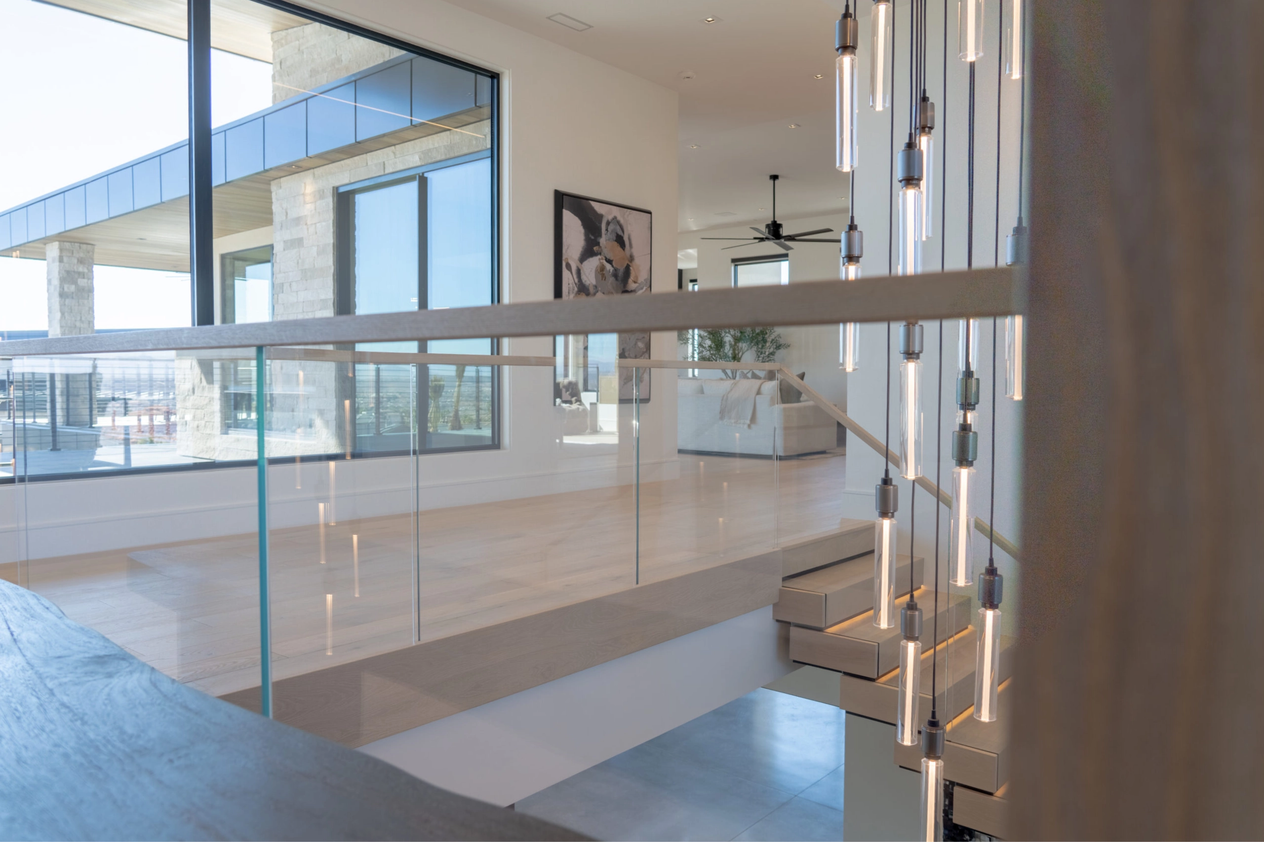 Looking over the glass railing toward stone walls and floor to ceiling windows