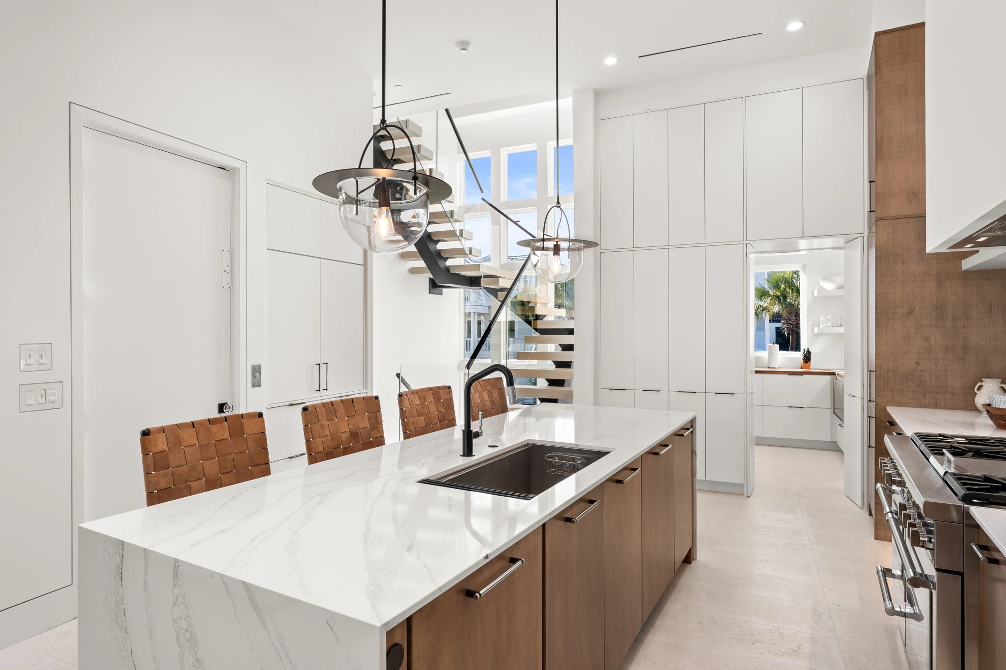 Kitchen island and range wall with the floating stair rising in the background