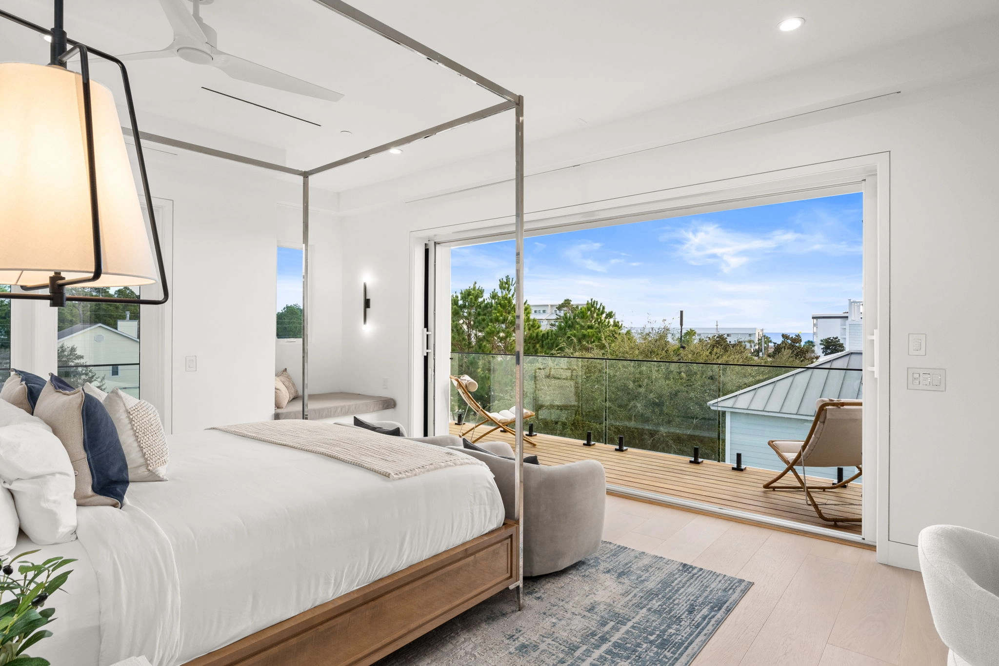 Bedroom opening onto a balcony with glass railing and treetop views