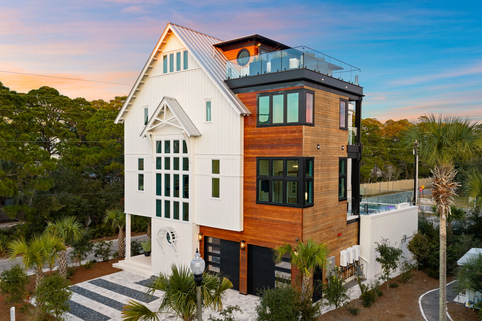 Street elevation at sunset showing wood siding, gables and rooftop glass railing