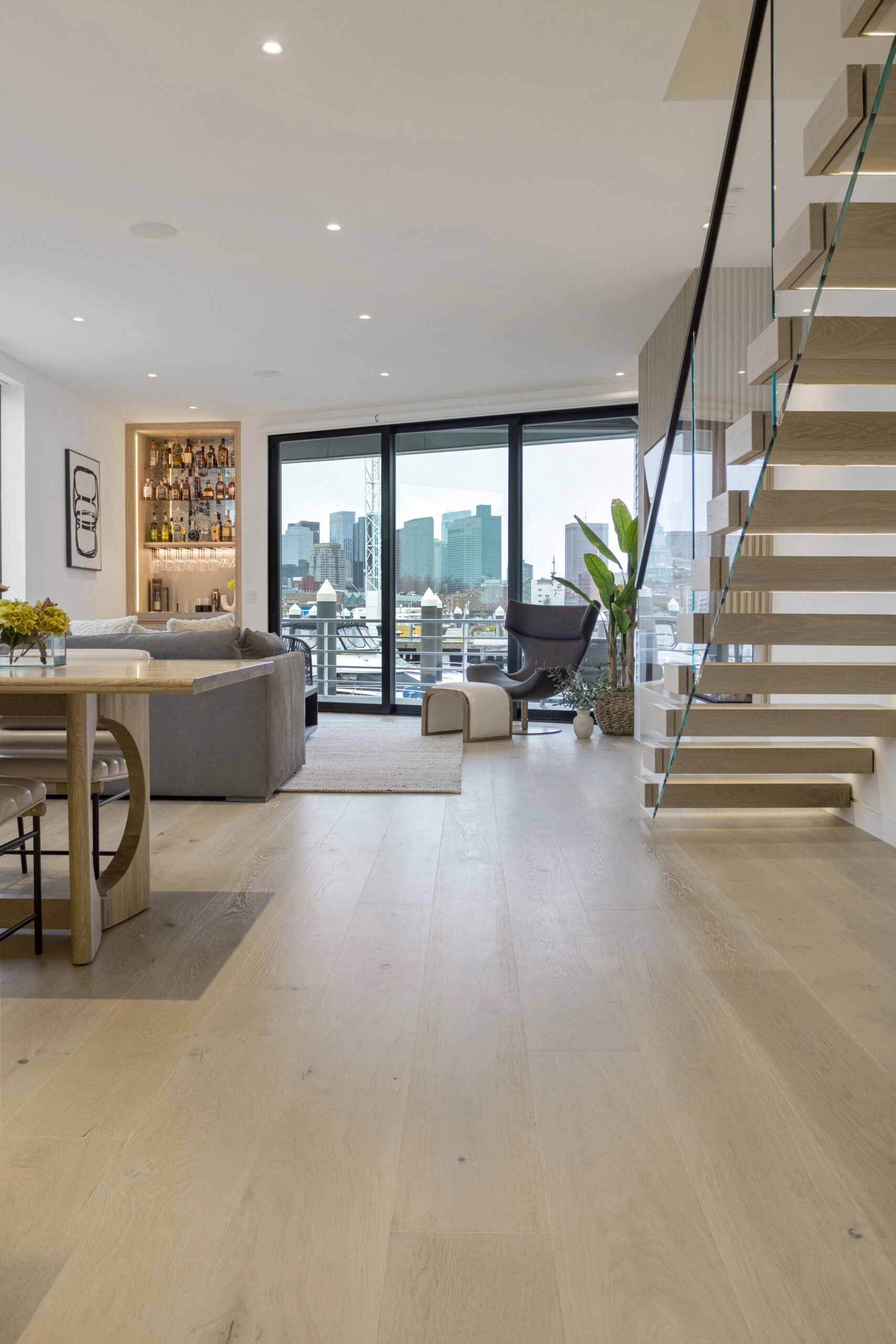 Living and dining space with city skyline beyond and the cantilevered stair at right