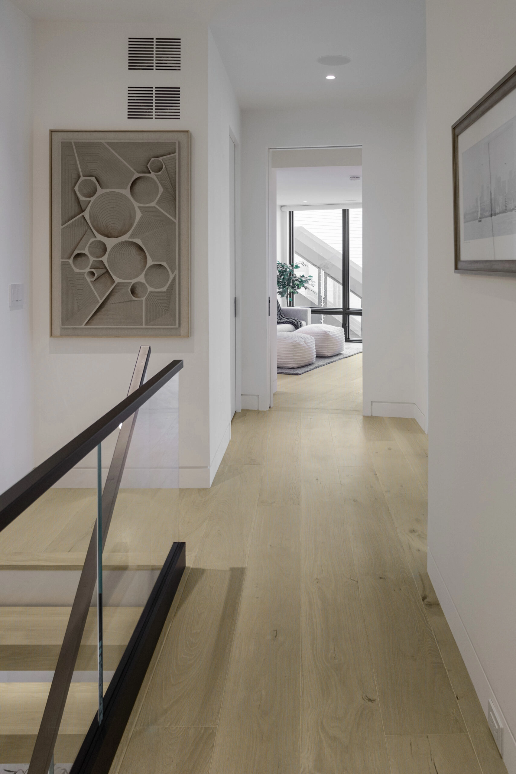Upstairs corridor with artwork and the glass stair railing at the opening