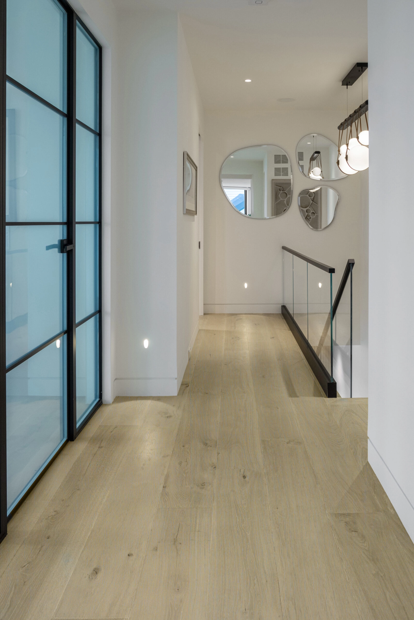 Upper hall with glass doors, mirrors and the glass-railed stair opening on the right