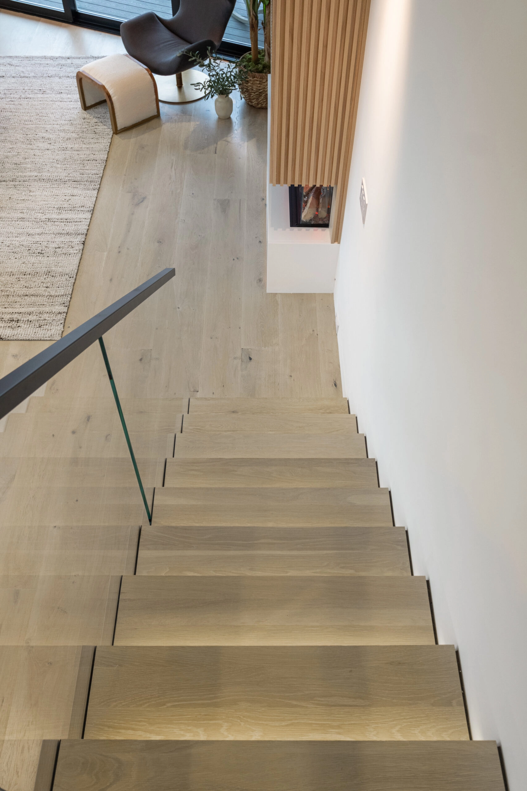 Descending view along a black handrail with tread lighting glowing at each edge