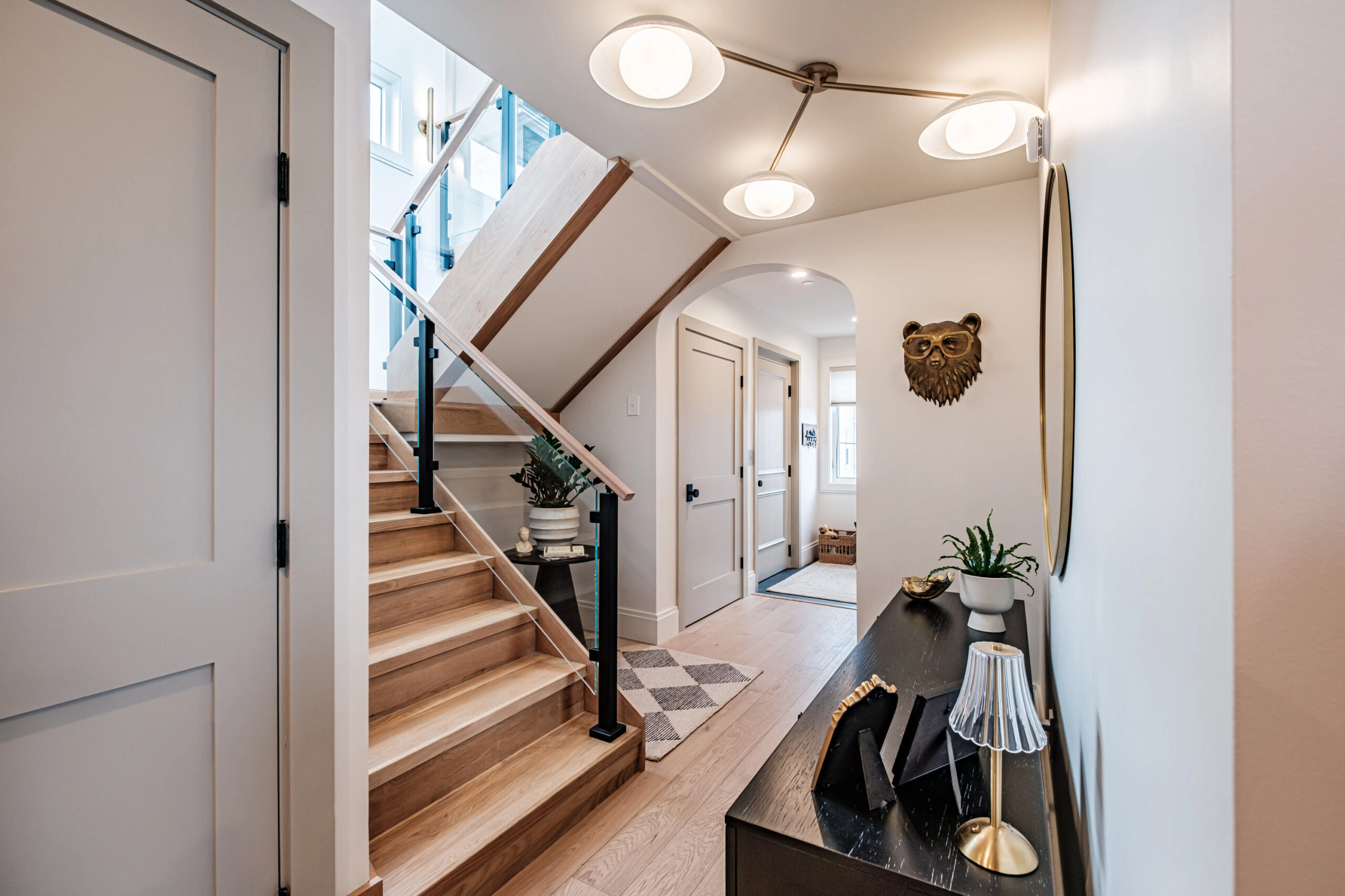 Entry with light fixture and the stair partly screened by glass railing panels