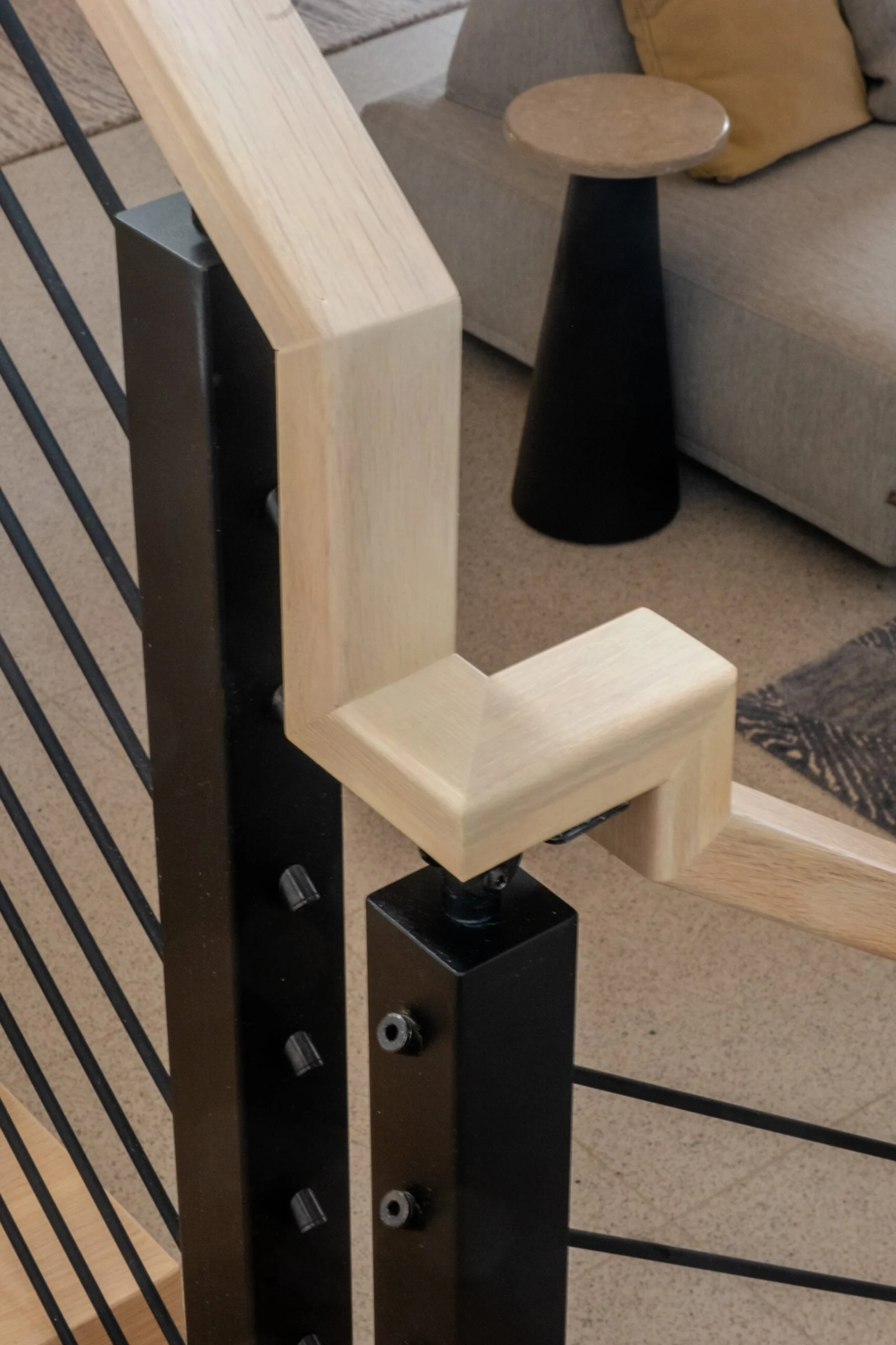 Wood handrail turning over a black post fitted with horizontal rods