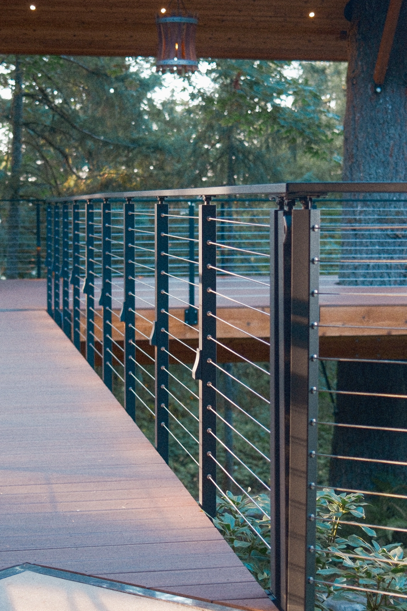 Black posts and taut cables lining a deck walkway at dusk