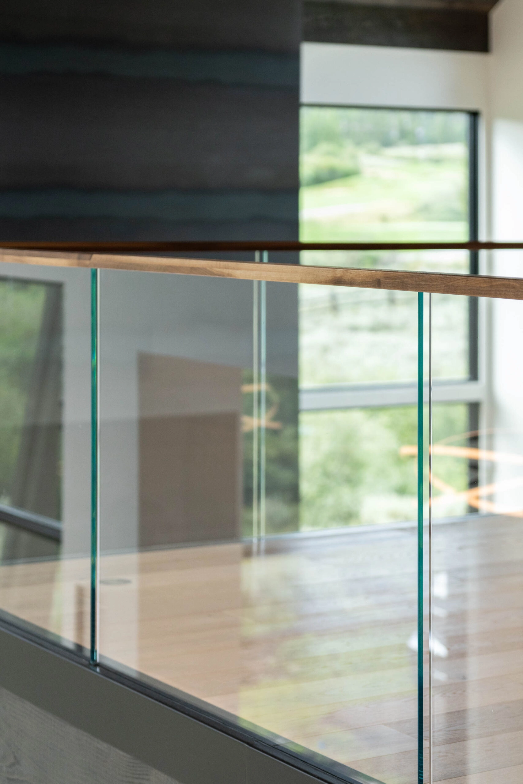 Glass panels capped by a slim wood rail with a dark plank wall behind