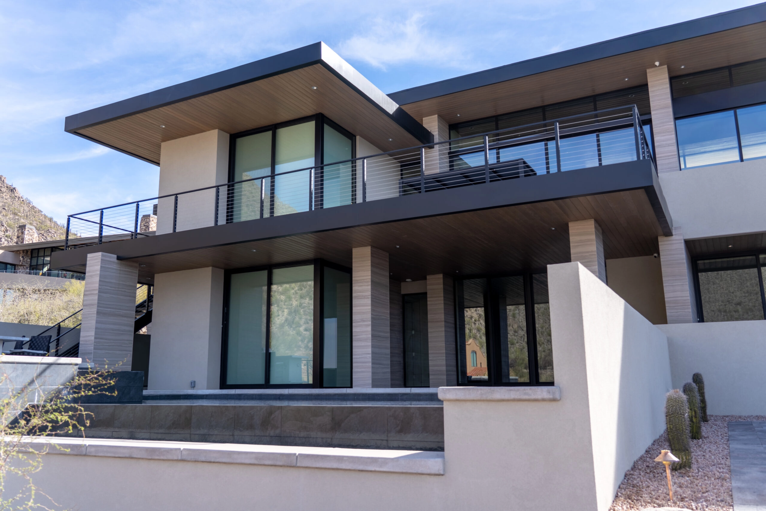 Two-story desert home with cable railing along its upper balcony and entry