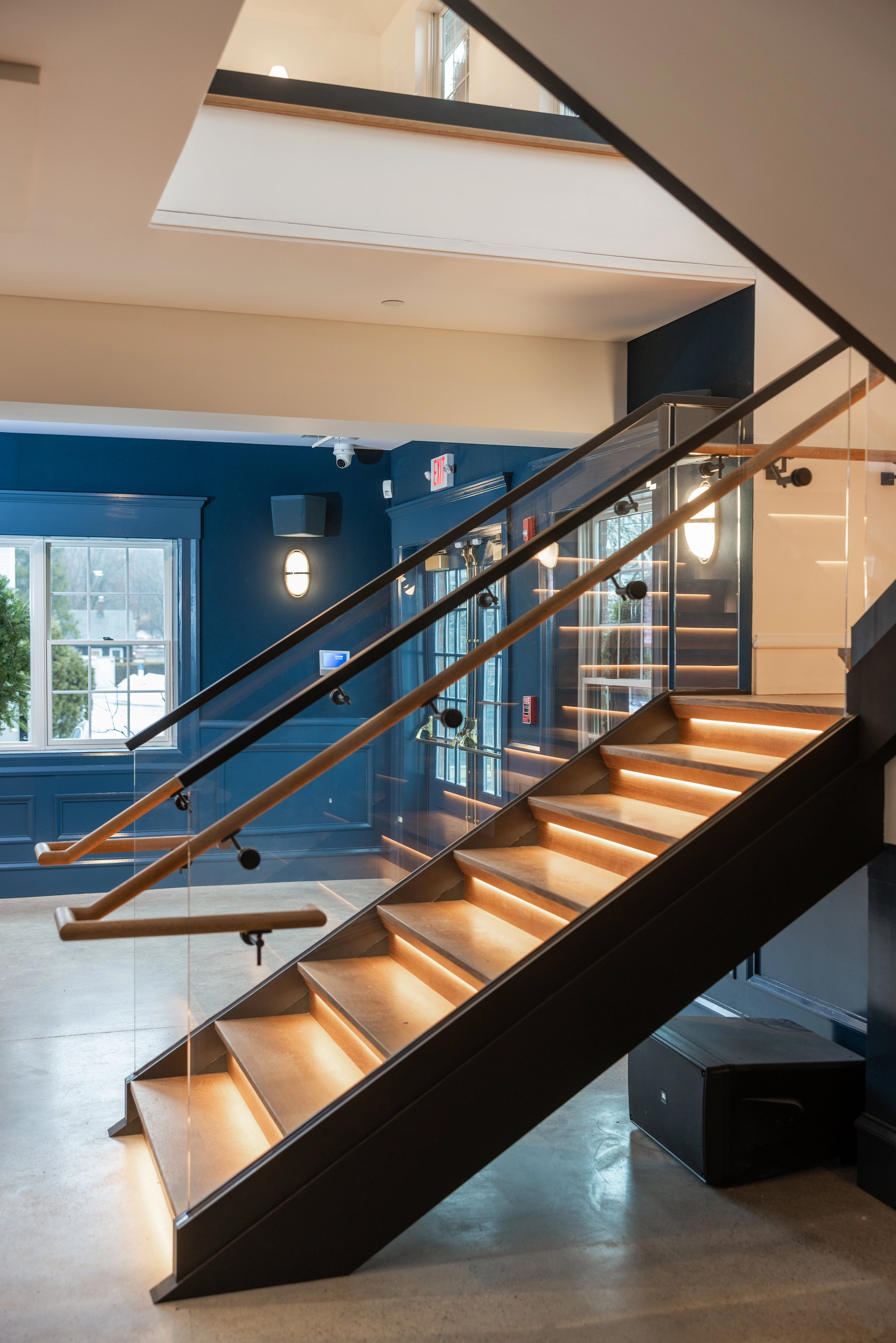 Angled view of the stair showing glass panels and a continuous wood handrail
