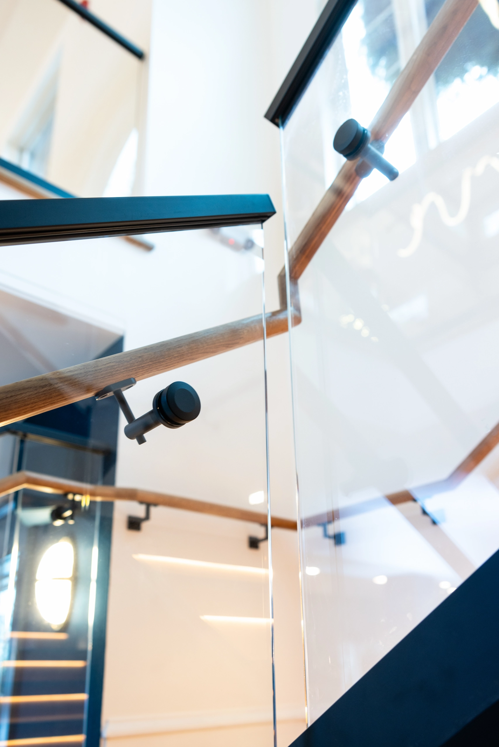 Looking up a glass panel where black and wood rails turn at a landing