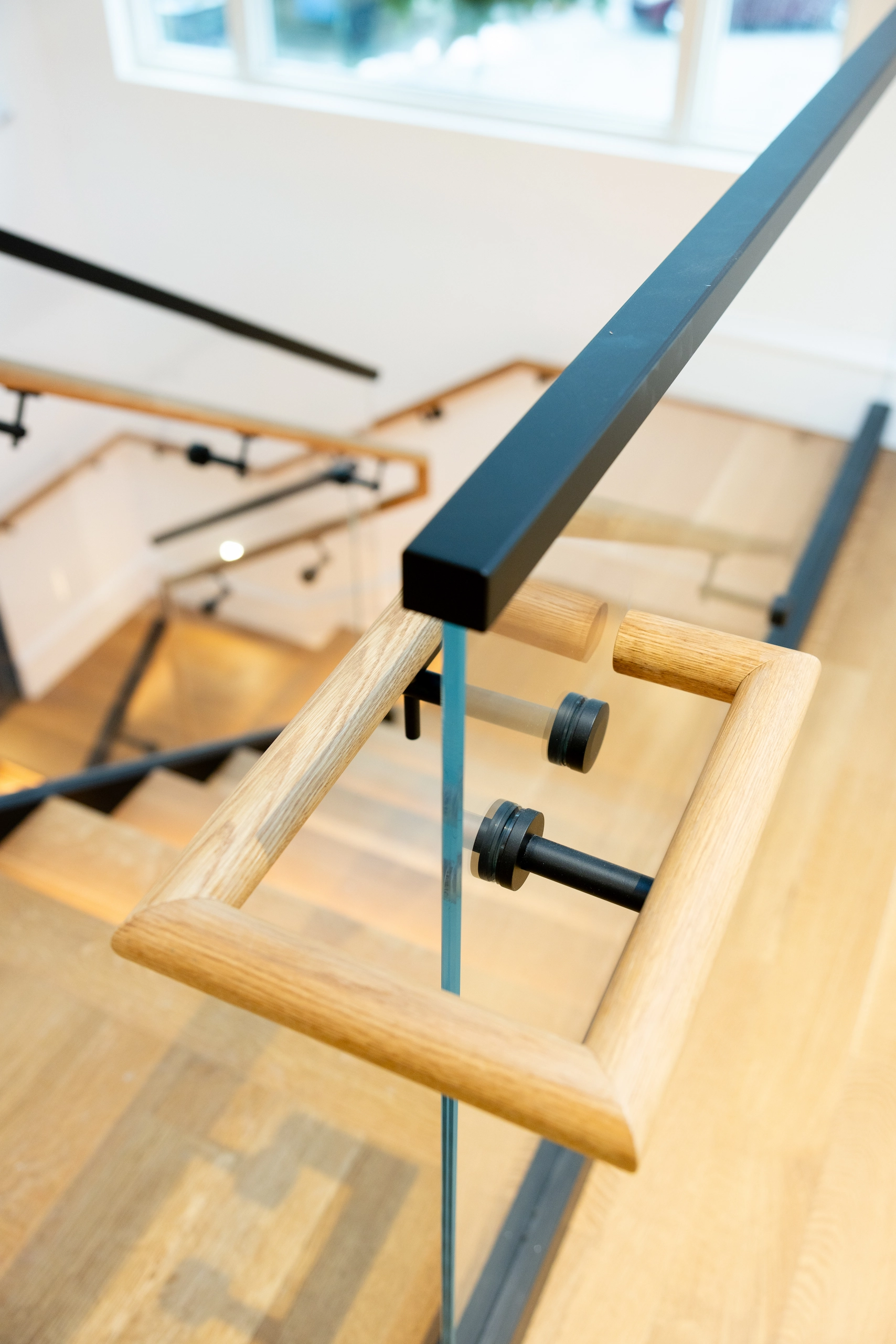 Detail of a handrail end fixed through glass above the floor below