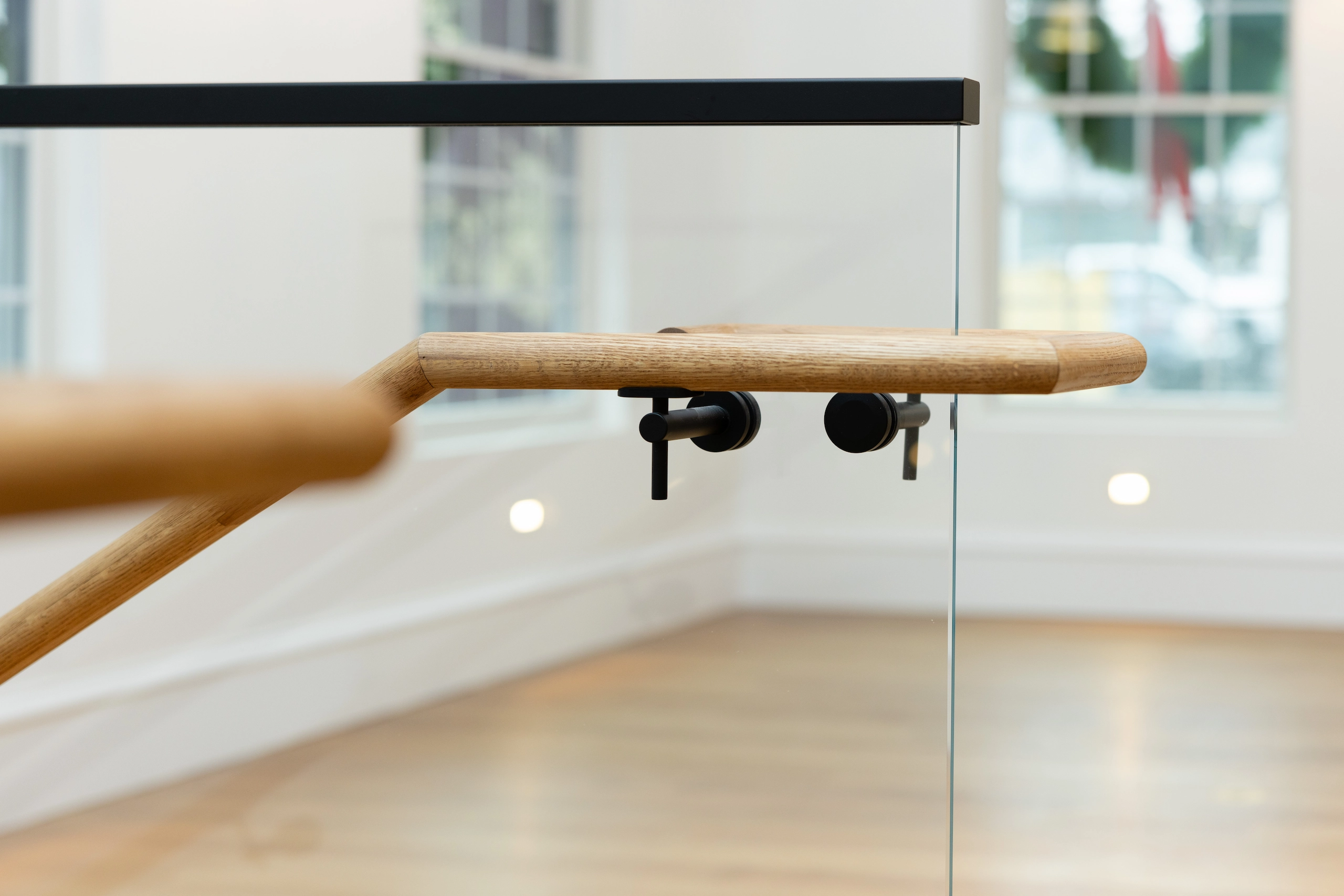 Handrail bracket and black top rail crossing a clear glass panel