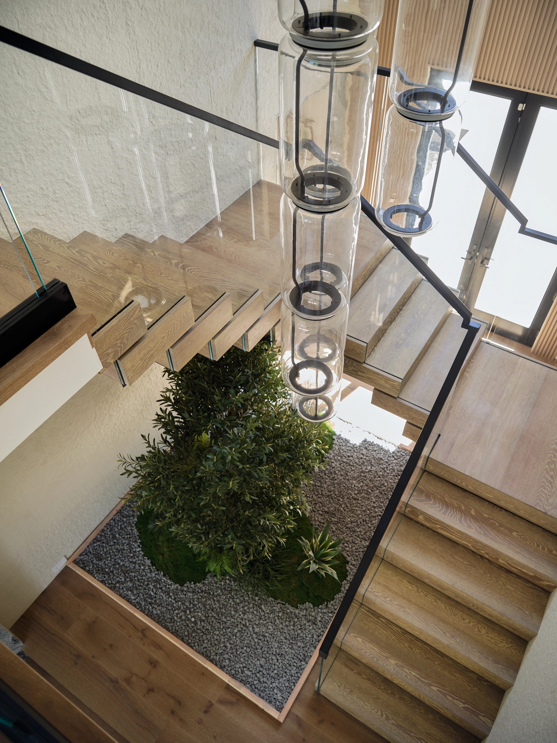 Looking down the stairwell at the planted stone bed ringed by glass railing