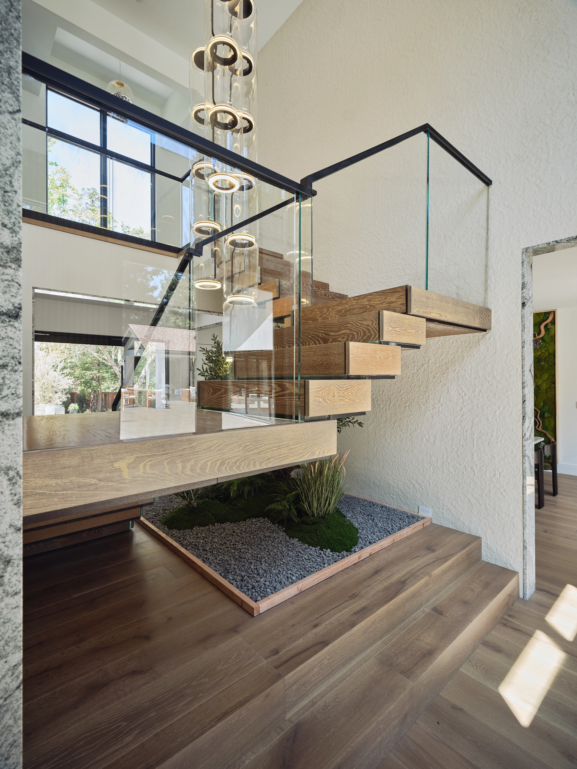 Full flight seen from the hall, glass panels and landscaped bed beneath the treads