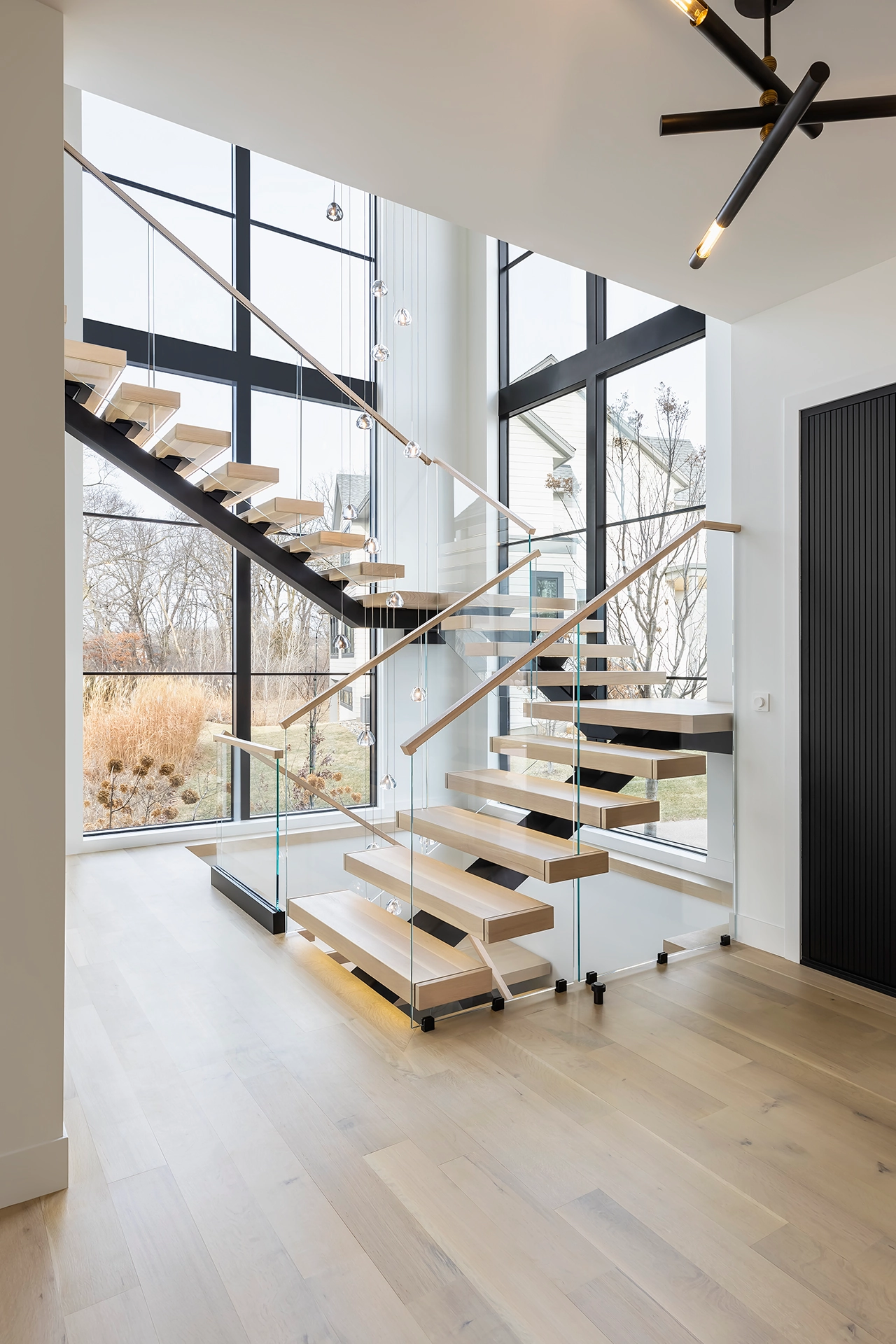 Open room where the stair meets a fluted black wall and plank flooring
