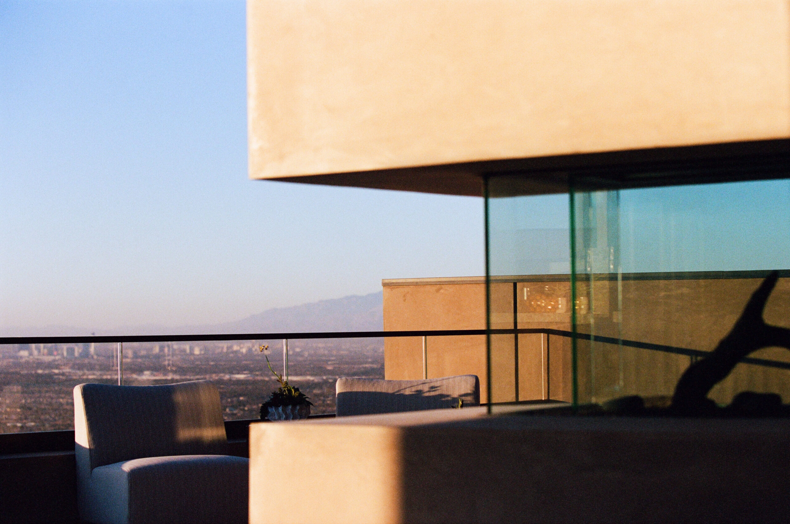 Sunset terrace with lounge chairs behind glass railing above a distant valley