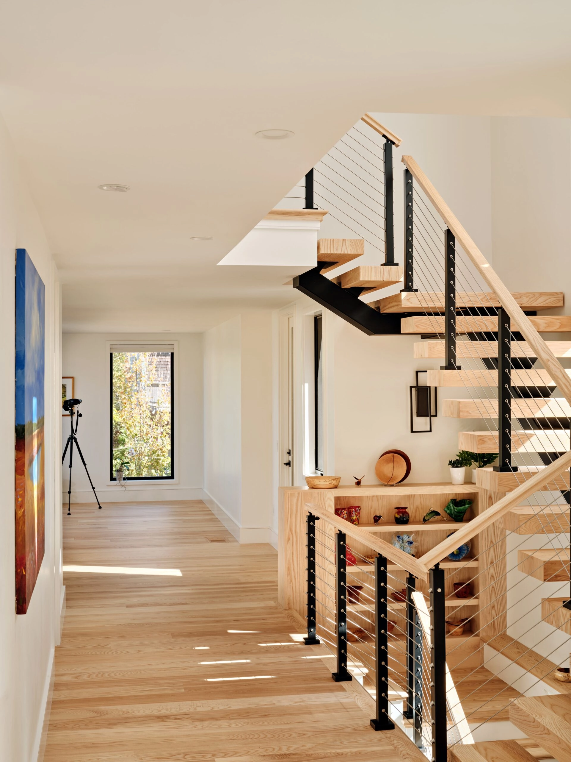 Hallway with artwork and the cable-railed stair rising at the far right