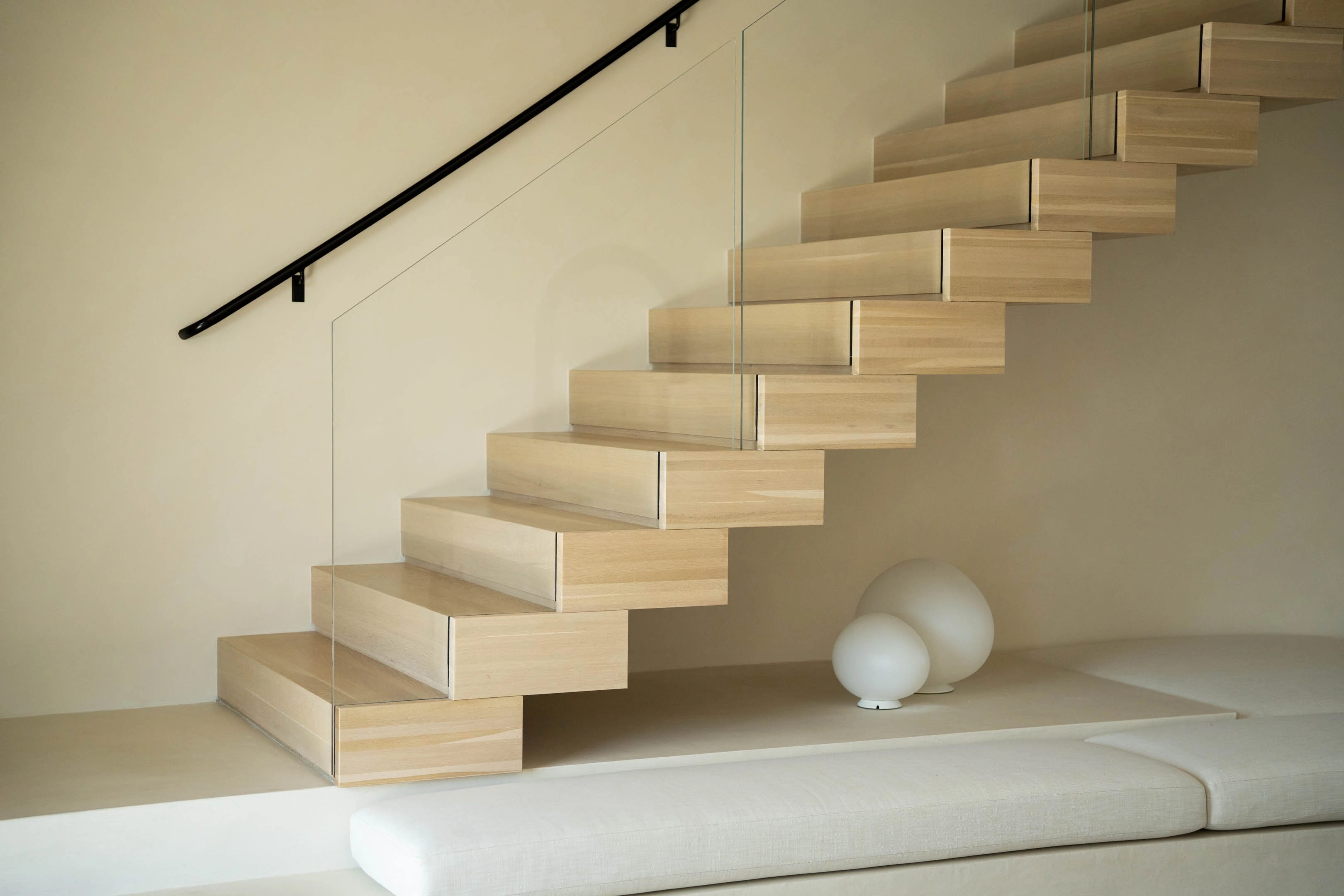 Stacked wood box treads against plaster with a slim black wall handrail