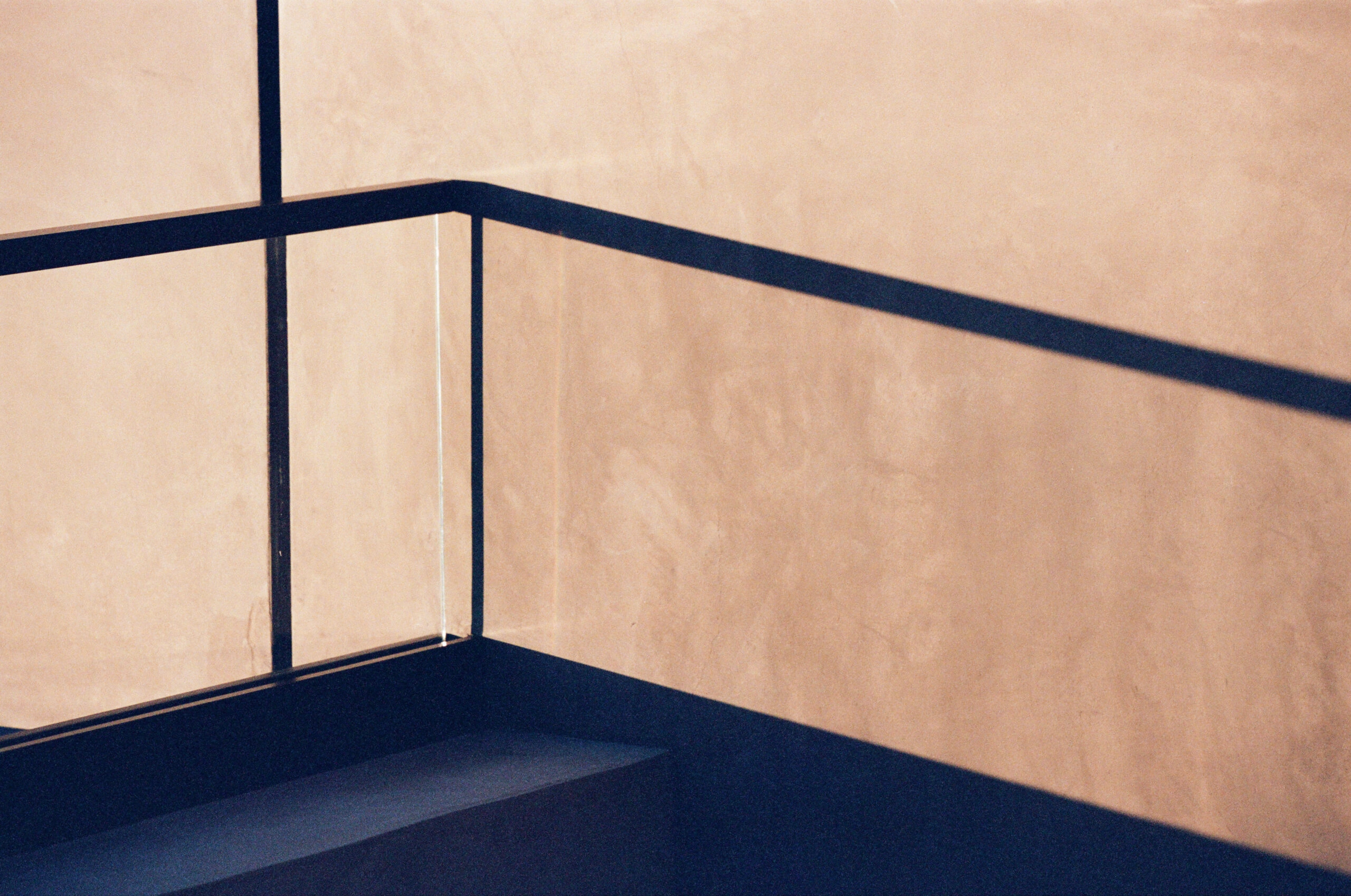 Dark rail lines tracing the corner of a warm stucco parapet