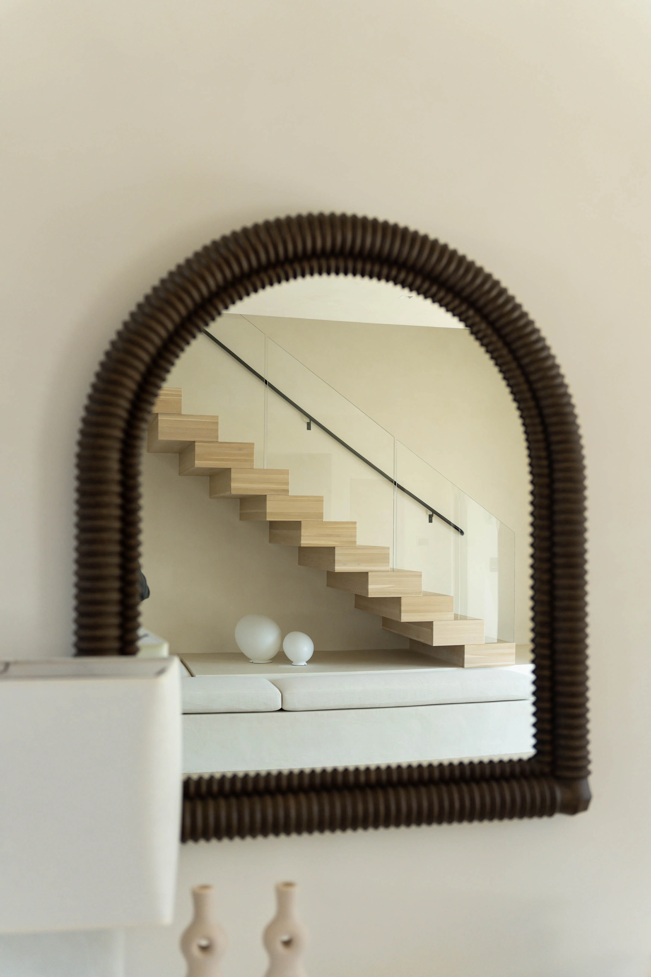 Arched mirror reflecting the floating treads and wall handrail behind