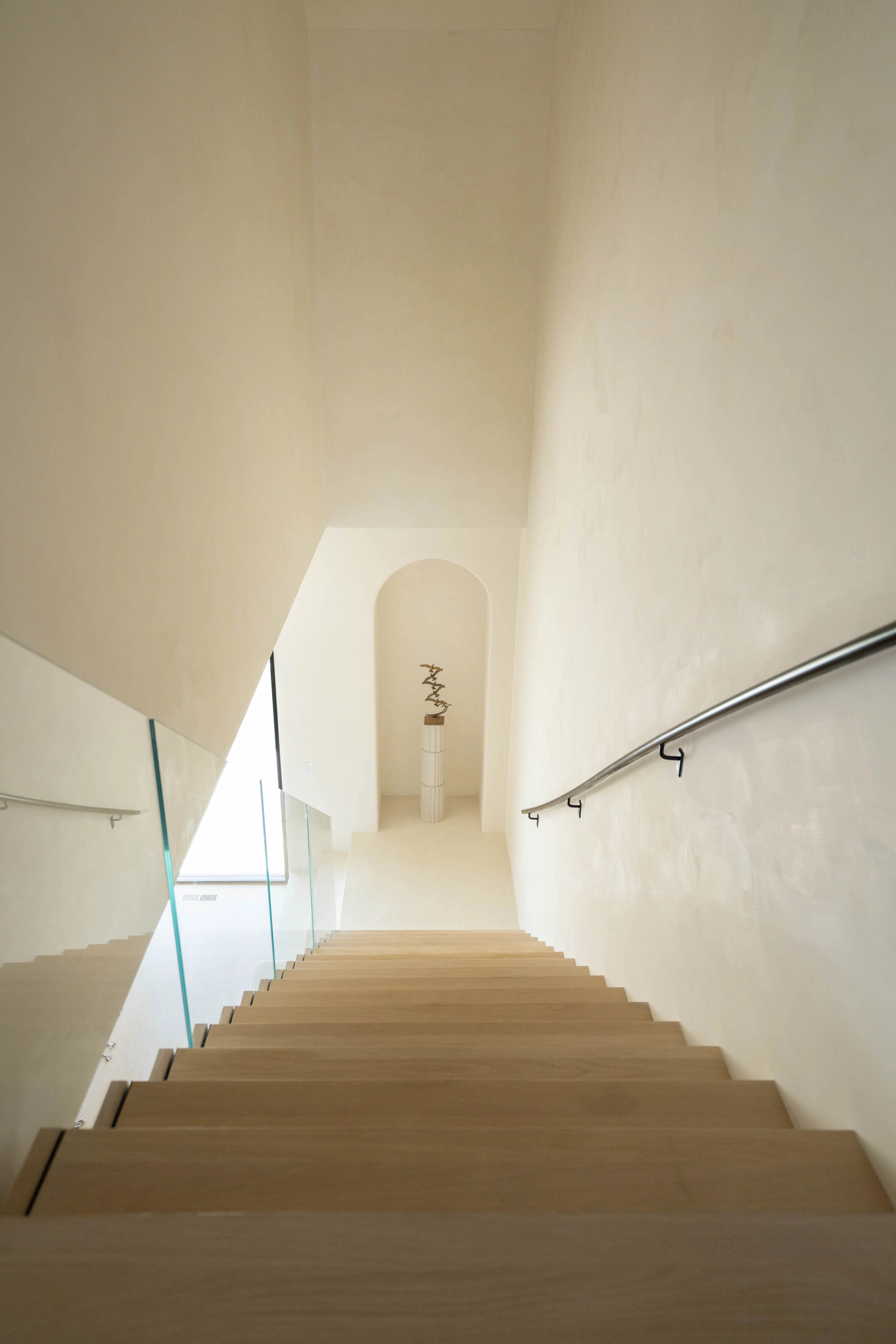 Looking down the treads toward an arched doorway at the end of the hall