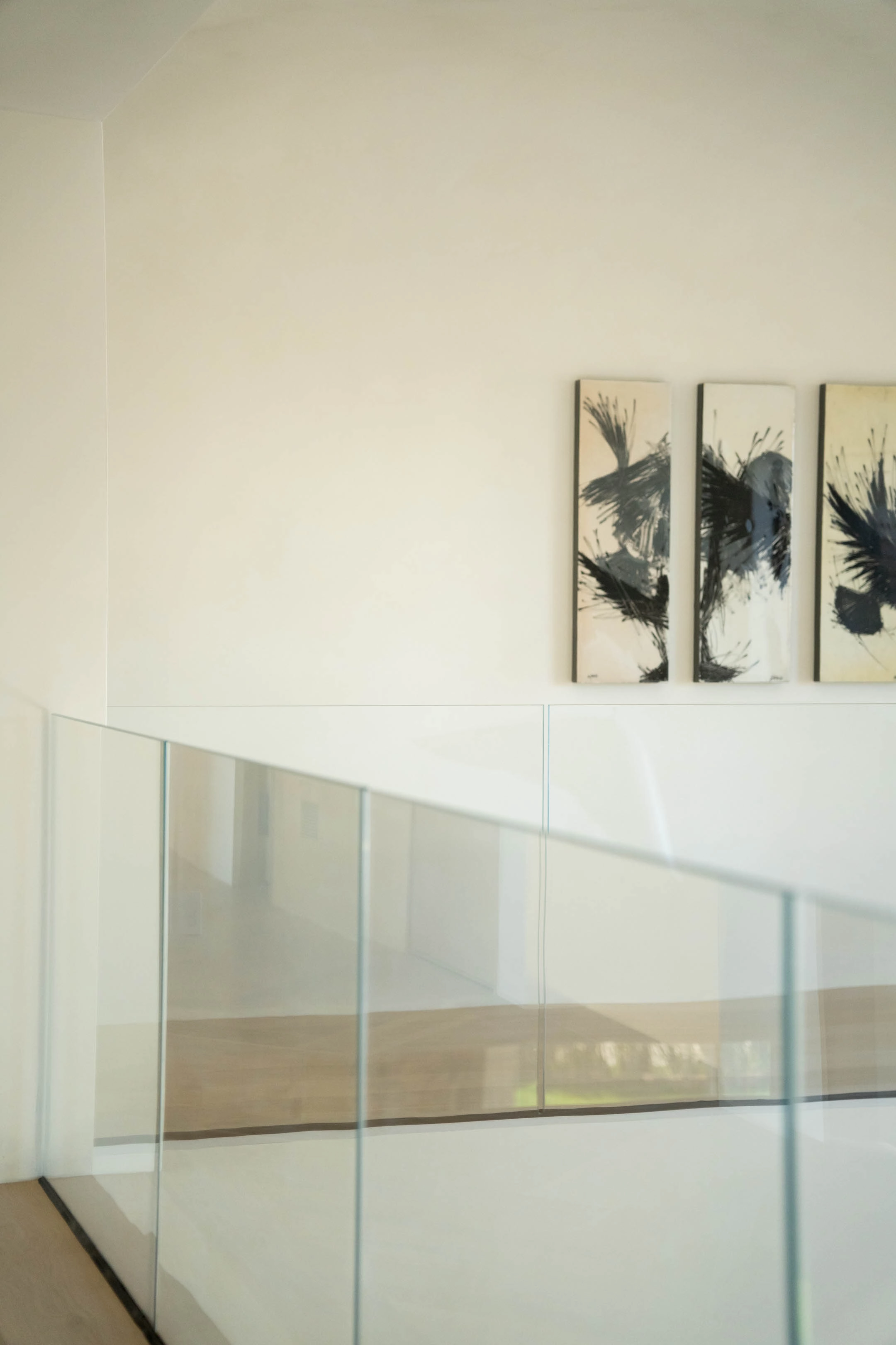 Glass balustrade on the upper landing beside a three-panel artwork