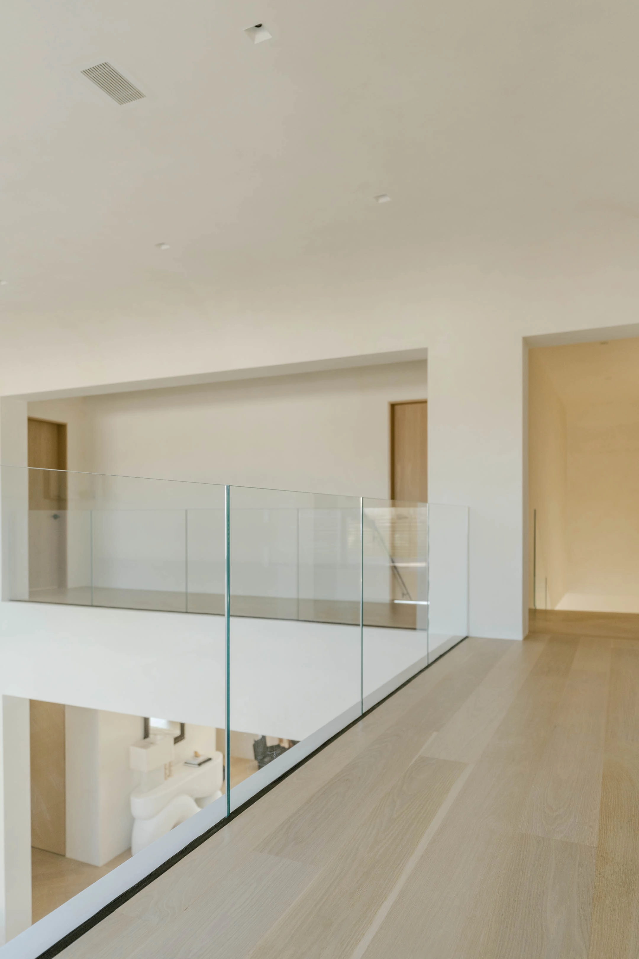 Upper hall with glass railing overlooking the level below
