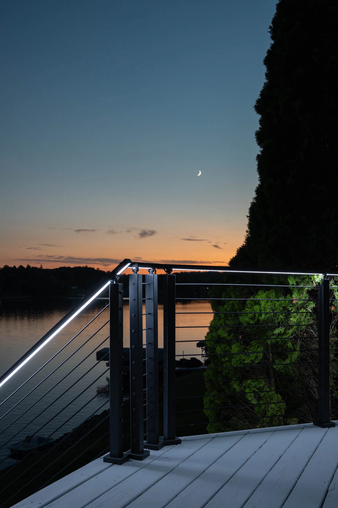 Corner of the railing at dusk with a lit handrail above the lake