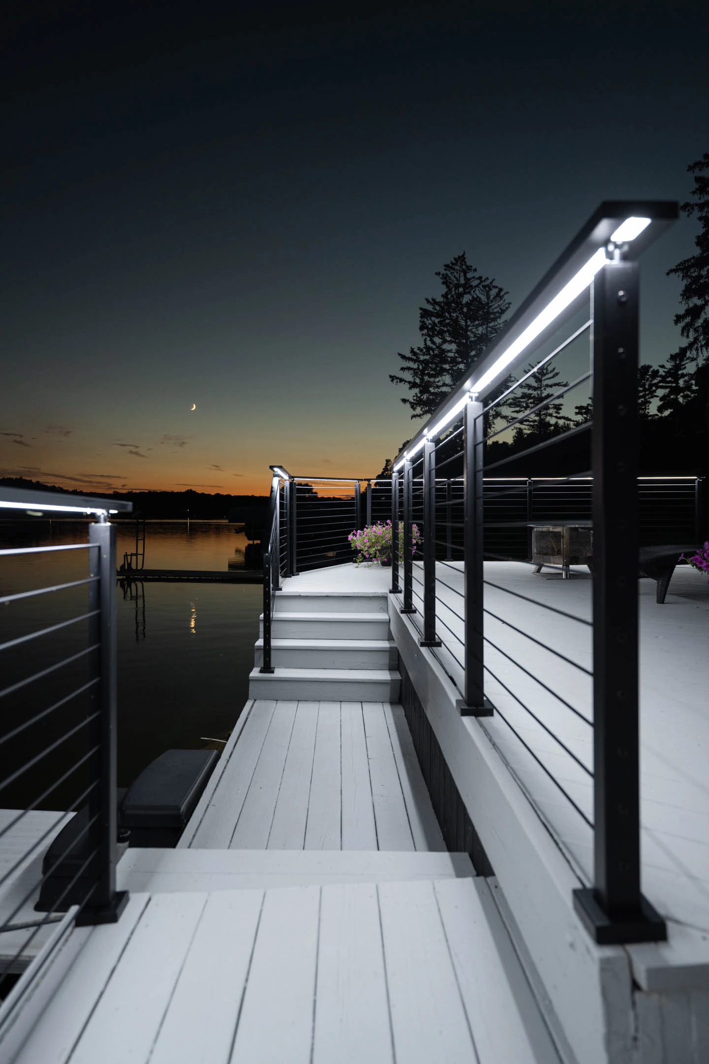 Night view down the deck walkway with both handrails lit toward the water