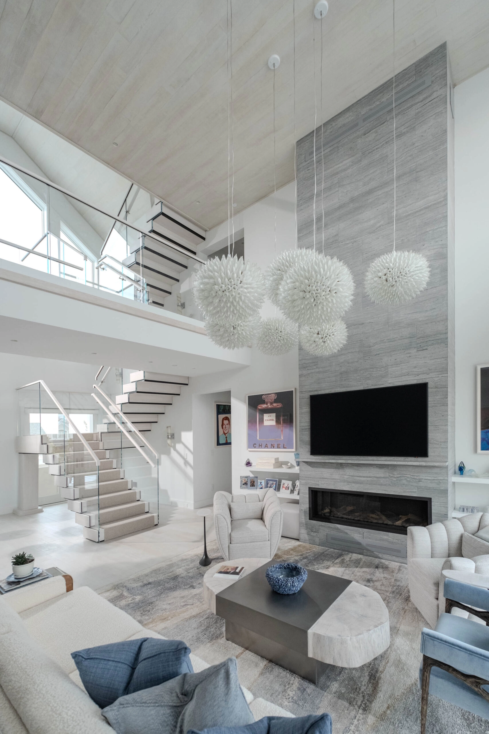 Double-height living room with pendant cluster and the stair rising along the far wall