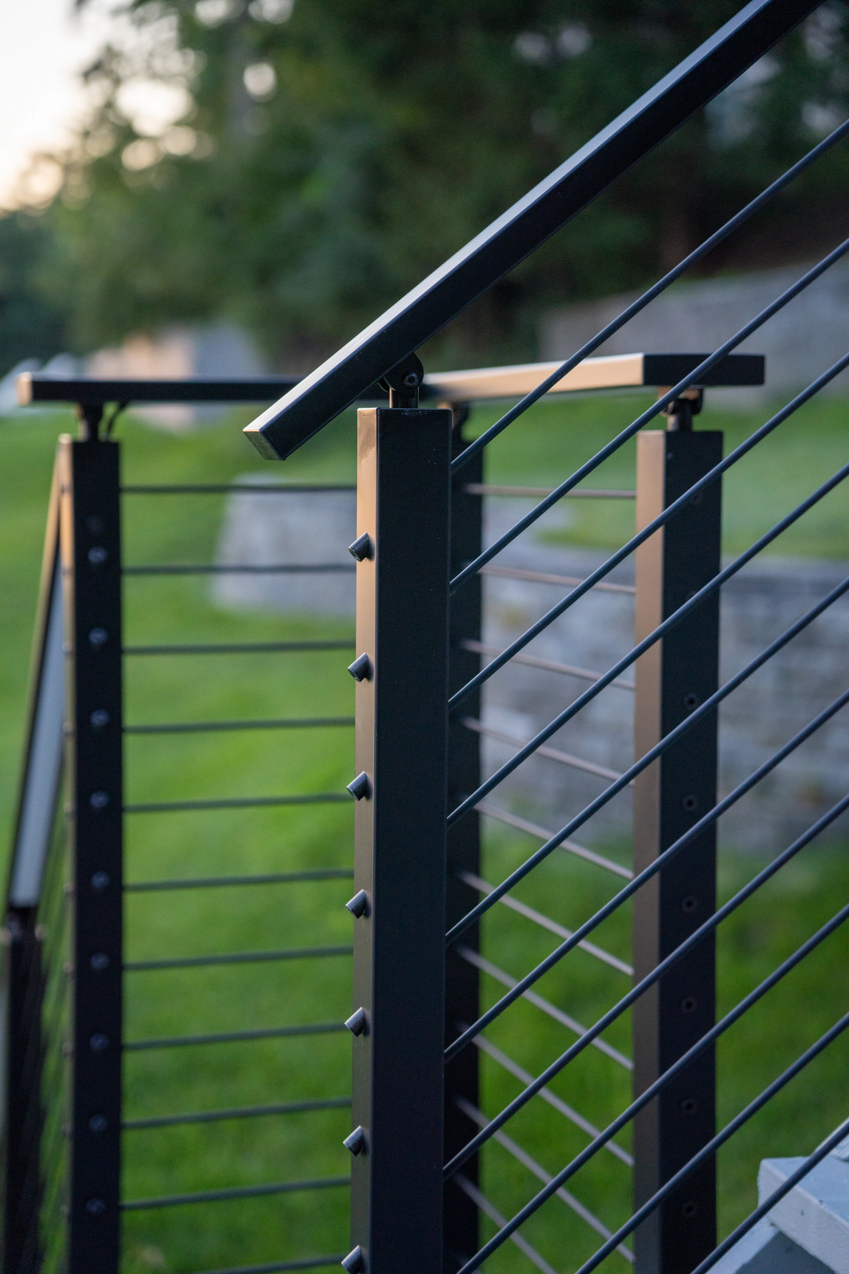 Dusk detail of a black post joining the top rail above horizontal rods