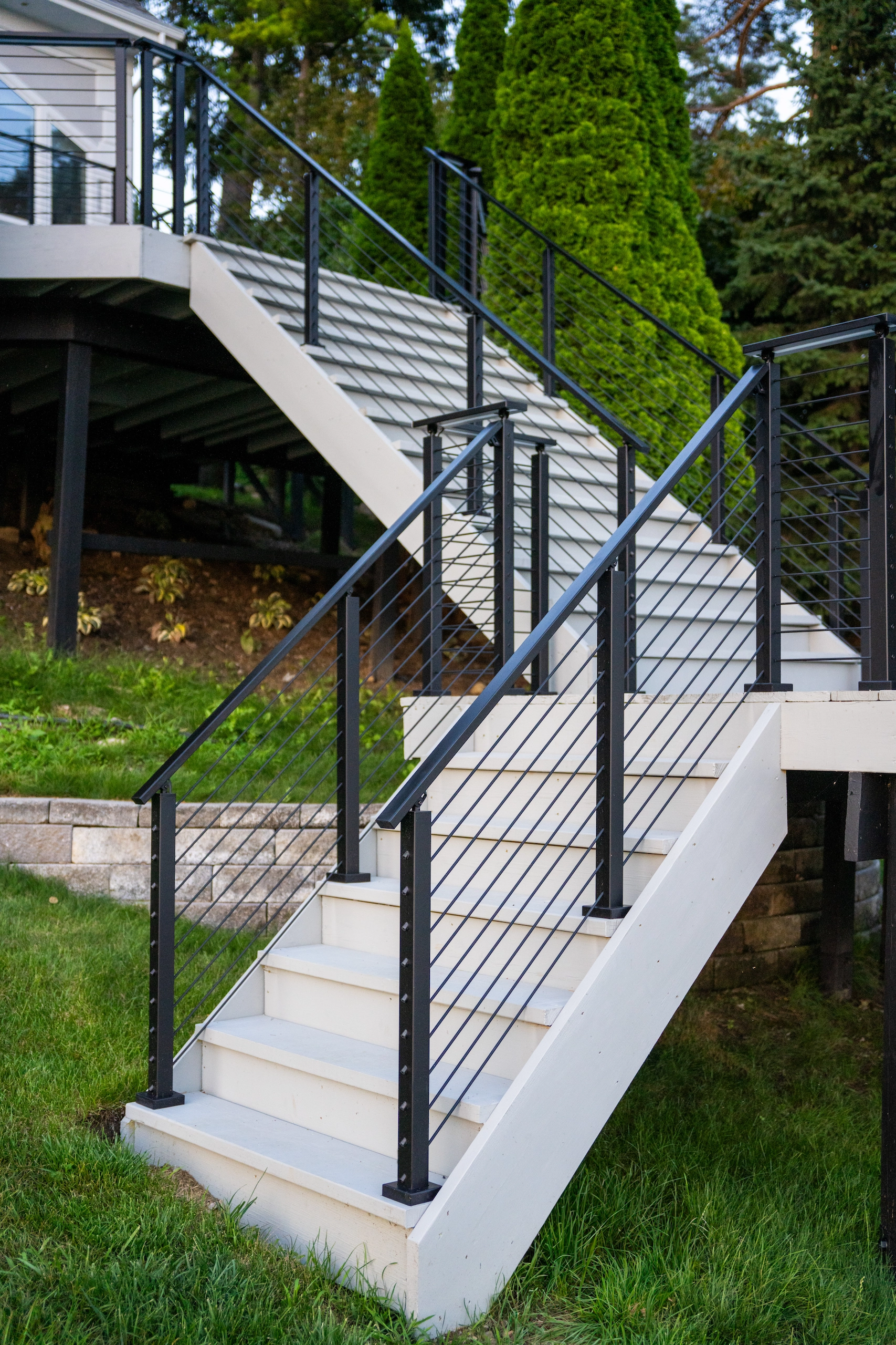 Wide daylight view of the white stair and black rod railing beside the lawn