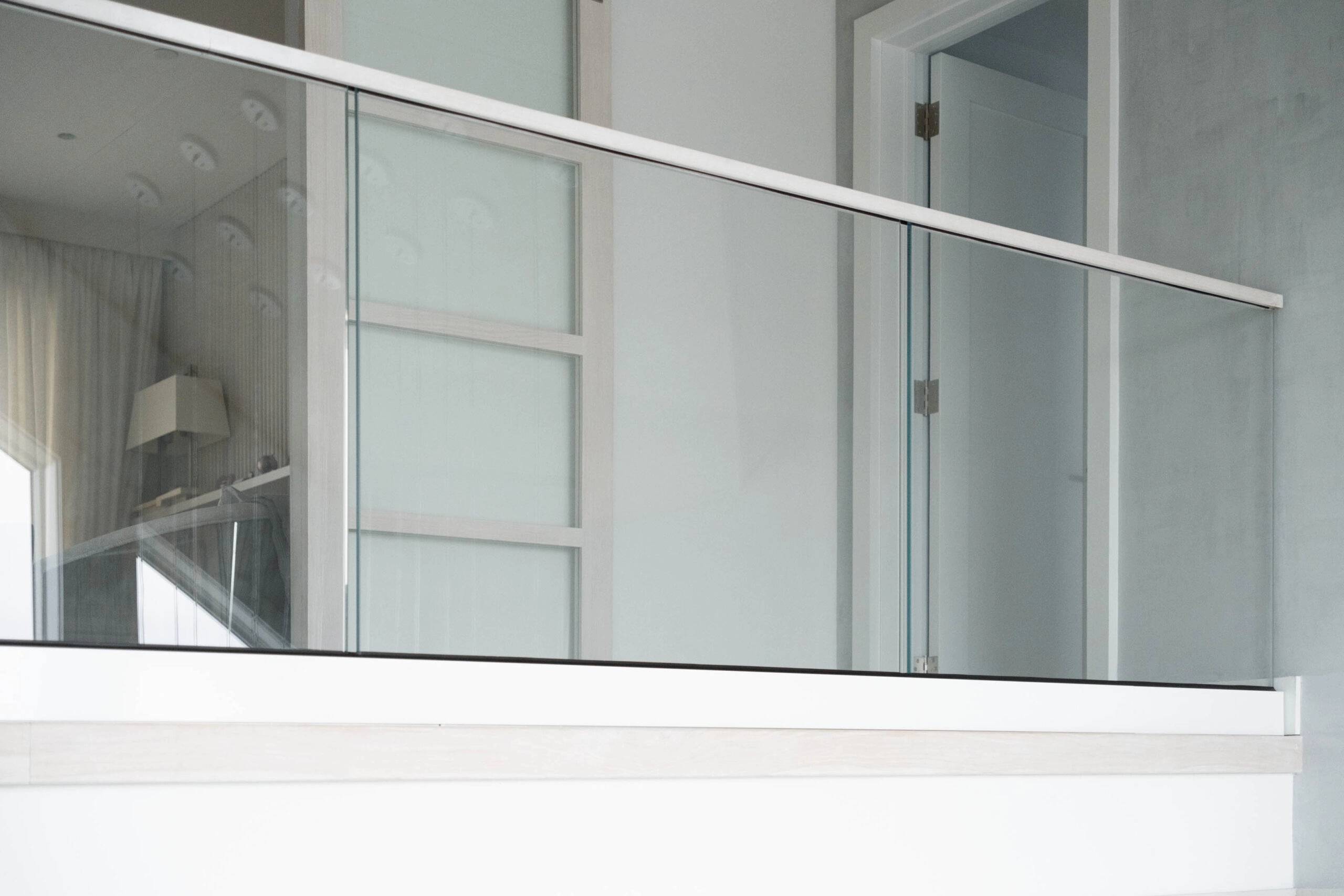 Glass balcony panels capped by a metal top rail at a doorway landing