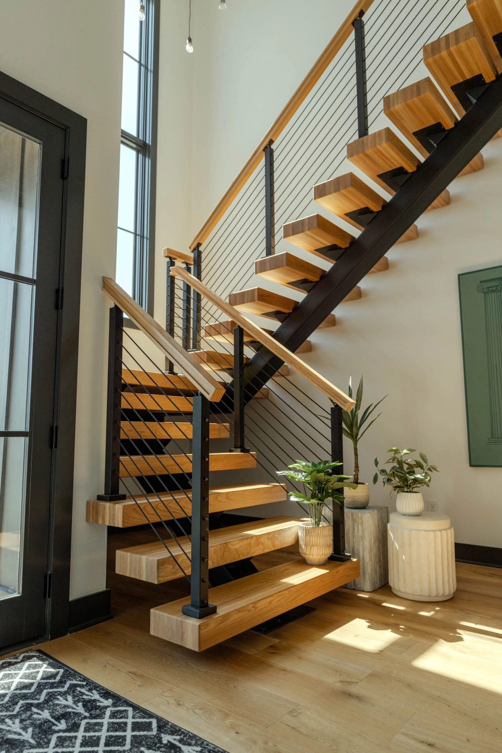 Entry stair with wood treads on a black stringer and rod railing under a wood handrail