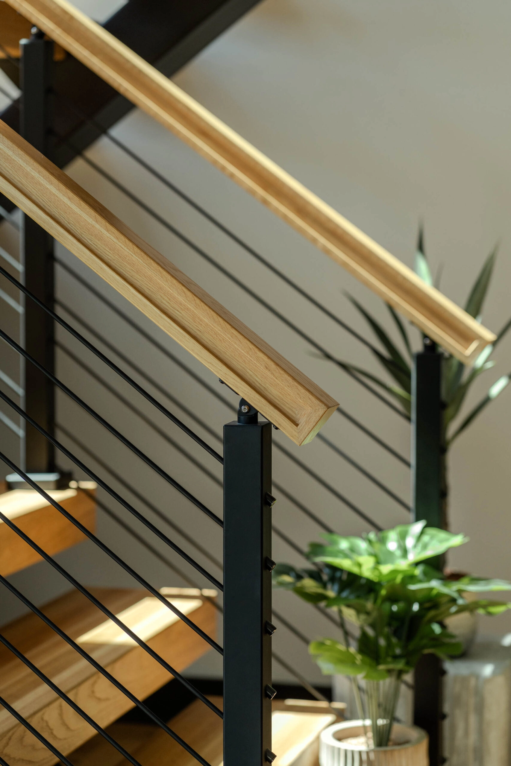 Wood handrail meeting a black post above evenly spaced horizontal rods