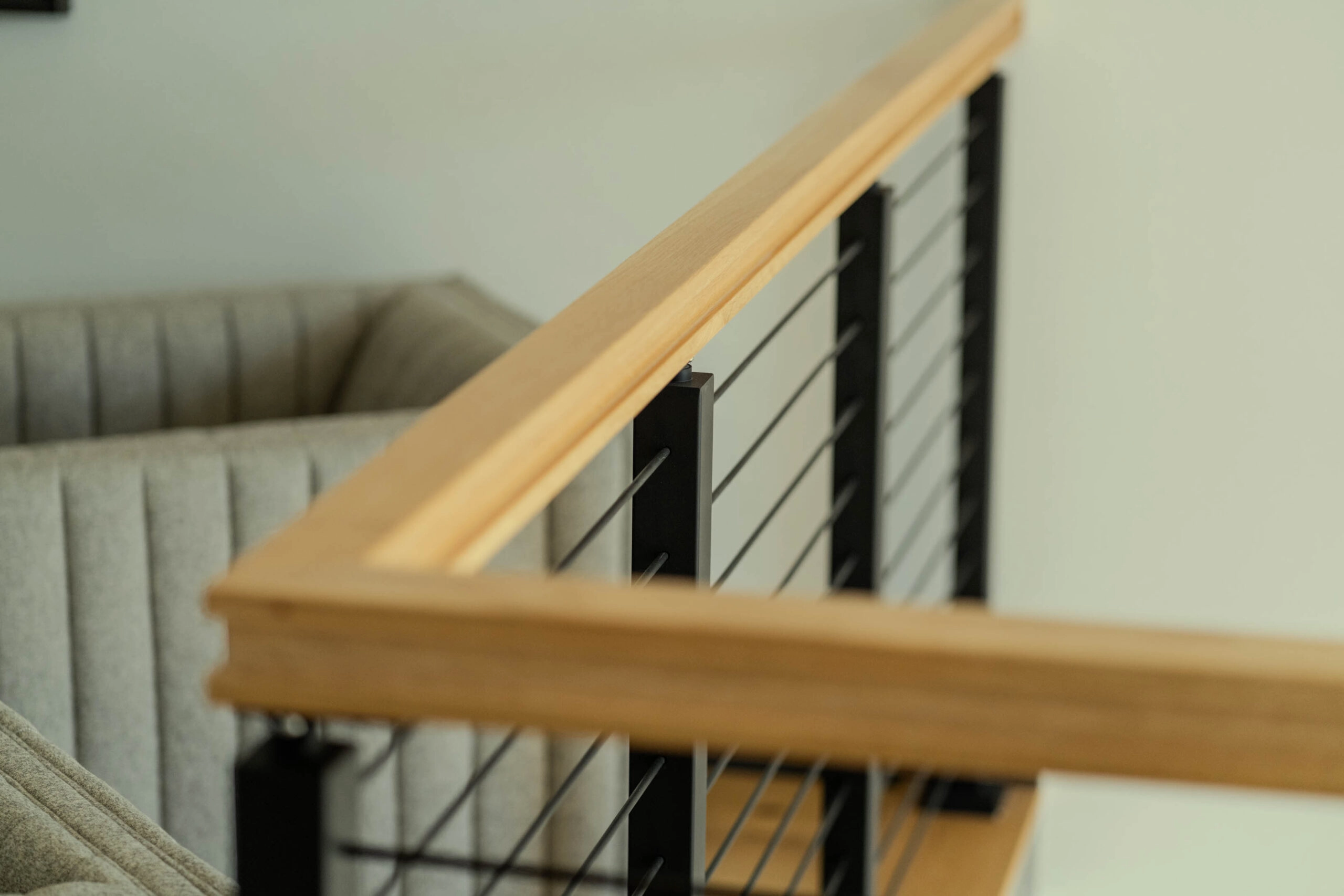 Corner where the wood handrail turns along the balcony above a sofa