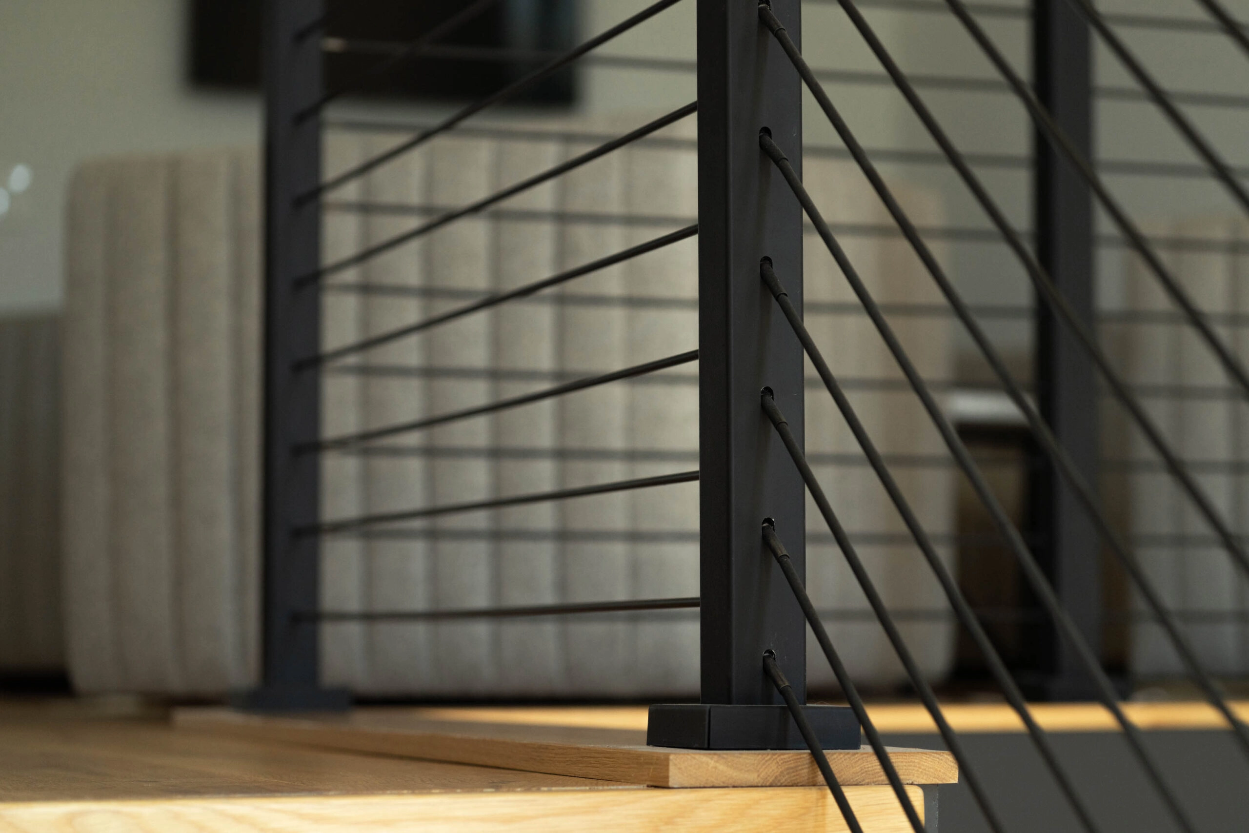 Black post base anchored to a tread with rods passing on both sides