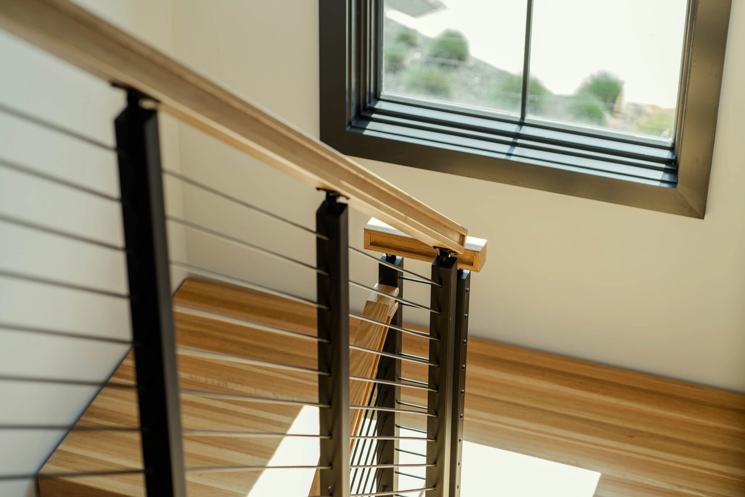 Looking down the balcony rail toward a deep-set window and stair below