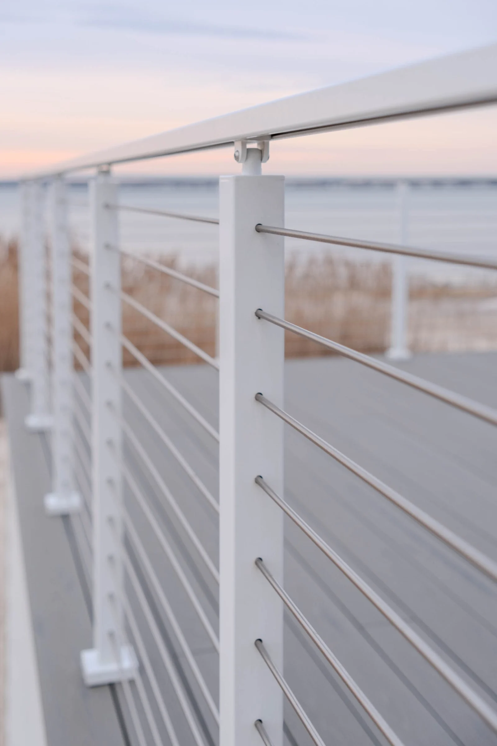 Angled close view of white posts and slim stainless rods in evening light