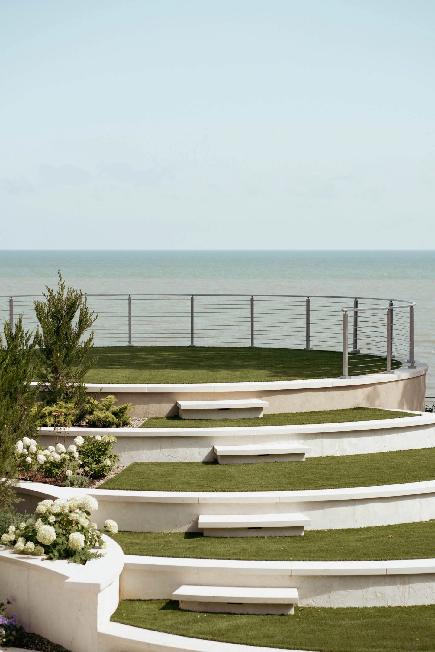 Terraced lawn steps leading down to a curved railing at the water's edge