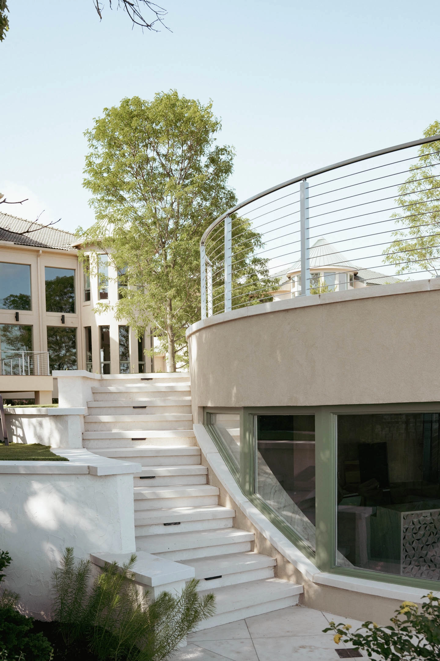 Stone steps climbing past a curved rod railing atop a rounded stucco wall